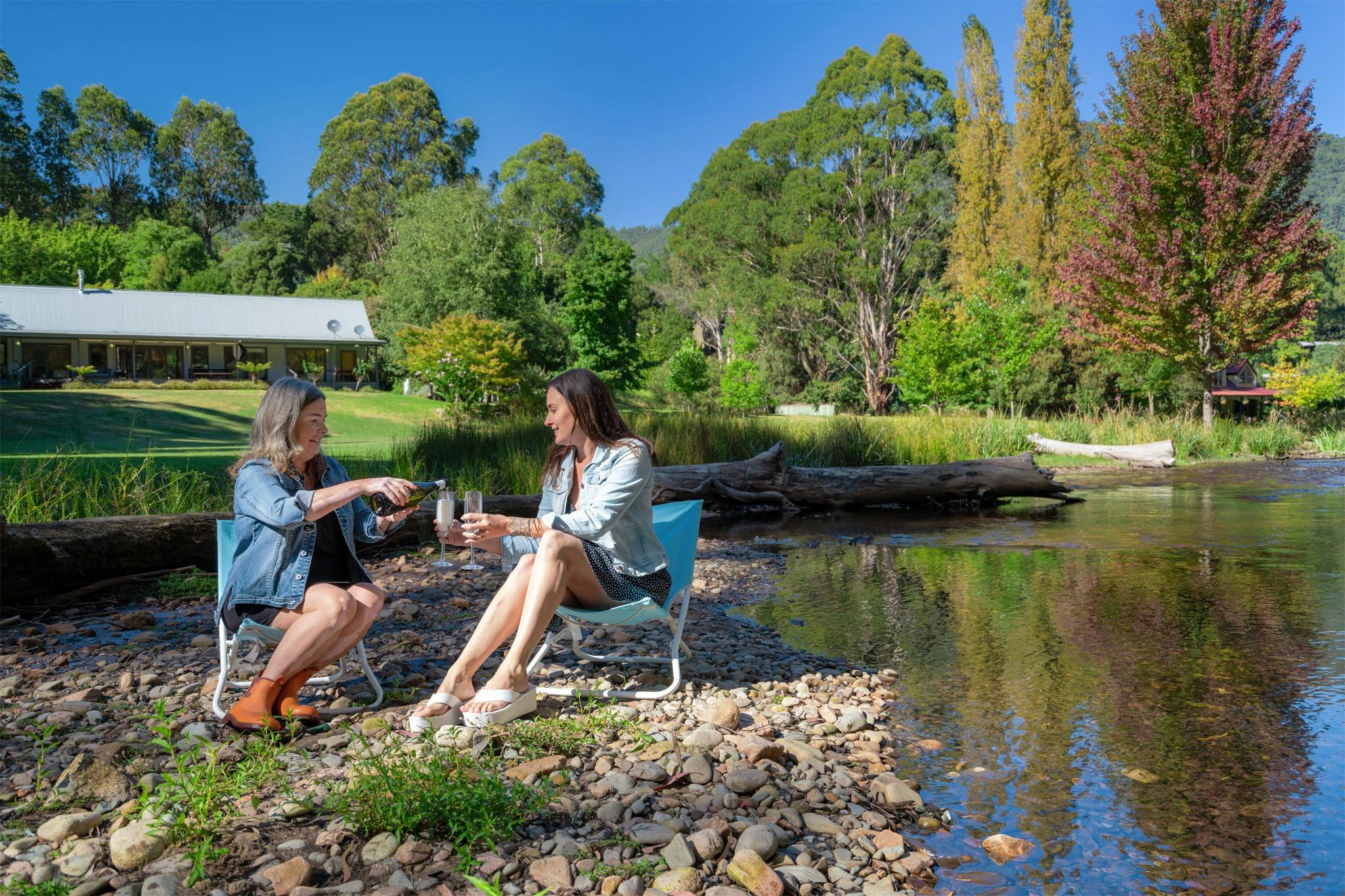 Friends enjoying wine by the water at Hume House Merrijig