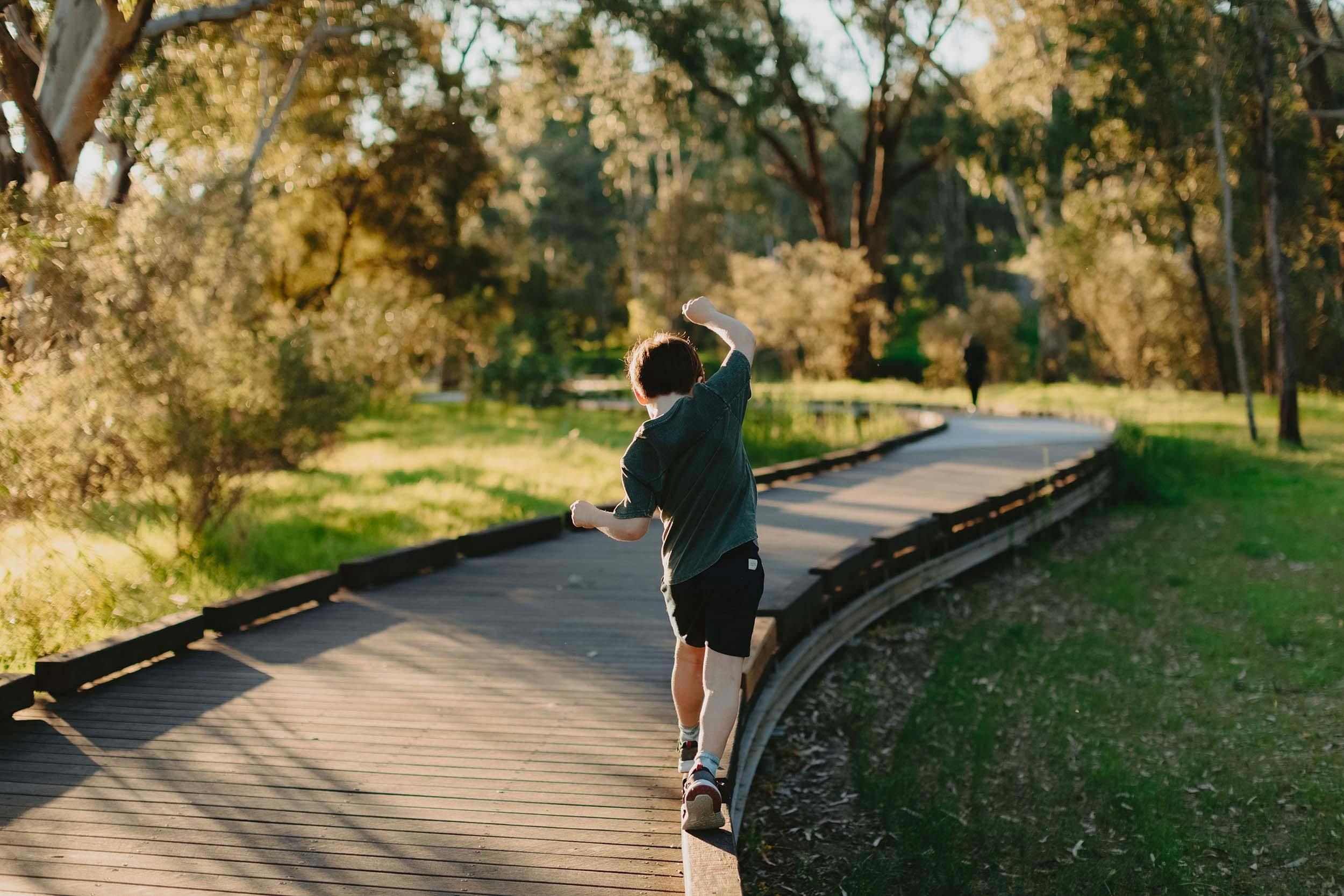 Child walking, balancing along the edge of walking trail