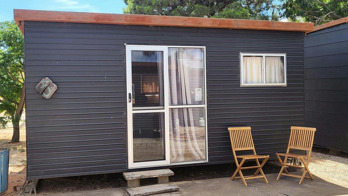 Black cabin with patio chairs at Kangaroo Lake Hotel Motel Accommodation
