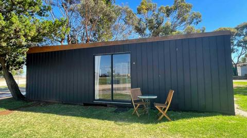 Black Cabin 6 with outdoor seating and grassy surroundings at Kangaroo Lake Hotel Motel