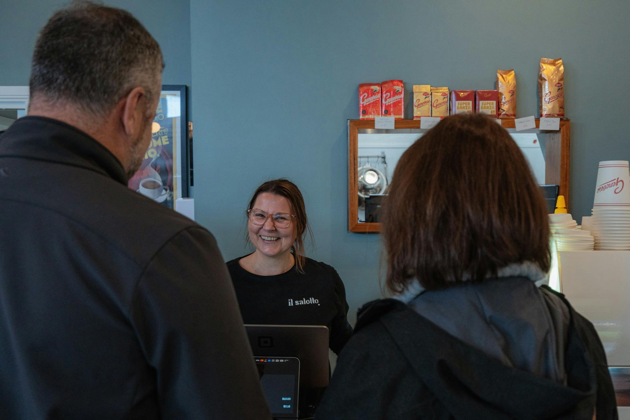 Two people standing at the counter while staff member smiles
