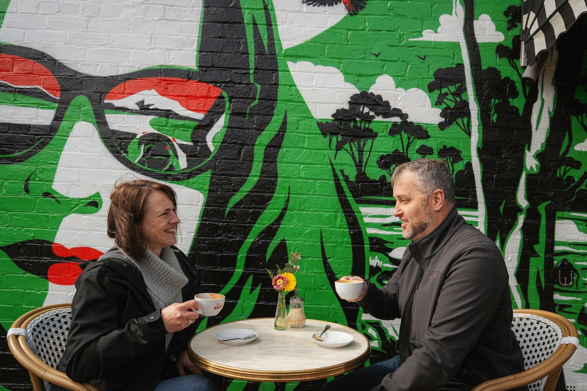 A mural with a woman with green hair and sunglasses with red, green, white and black in the frames