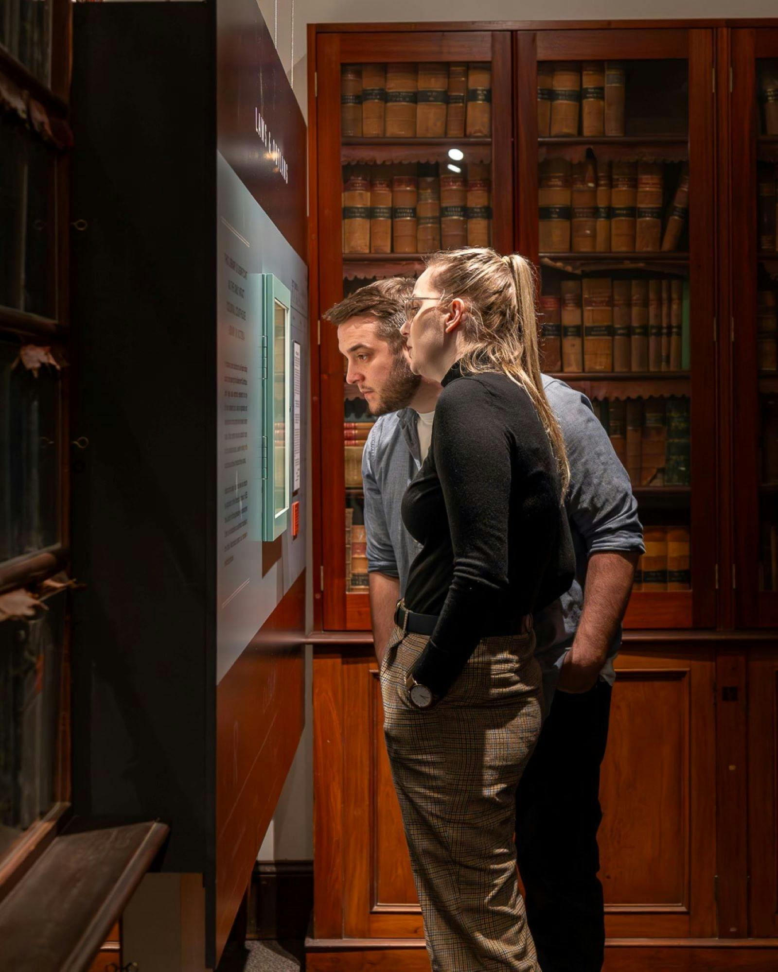 Two people looking into glass window display with old law library  books  in the background