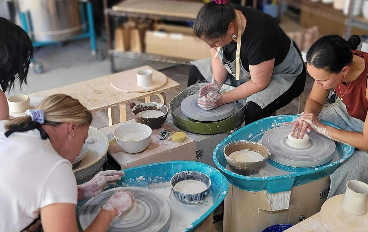 Beginner wheel-throwing students in full focus