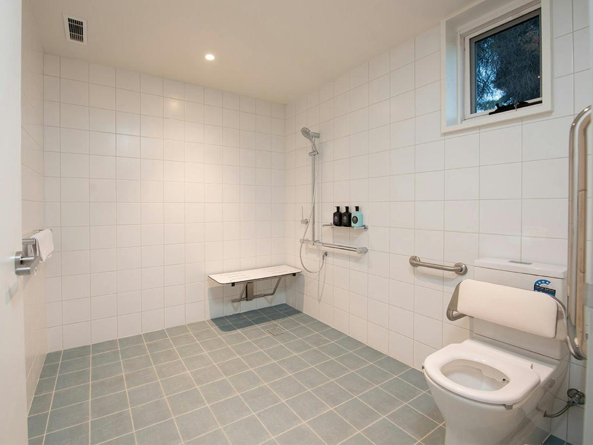 bathroom with toilet and handrails and shower in the Kar-Rama Super Easy Access Room