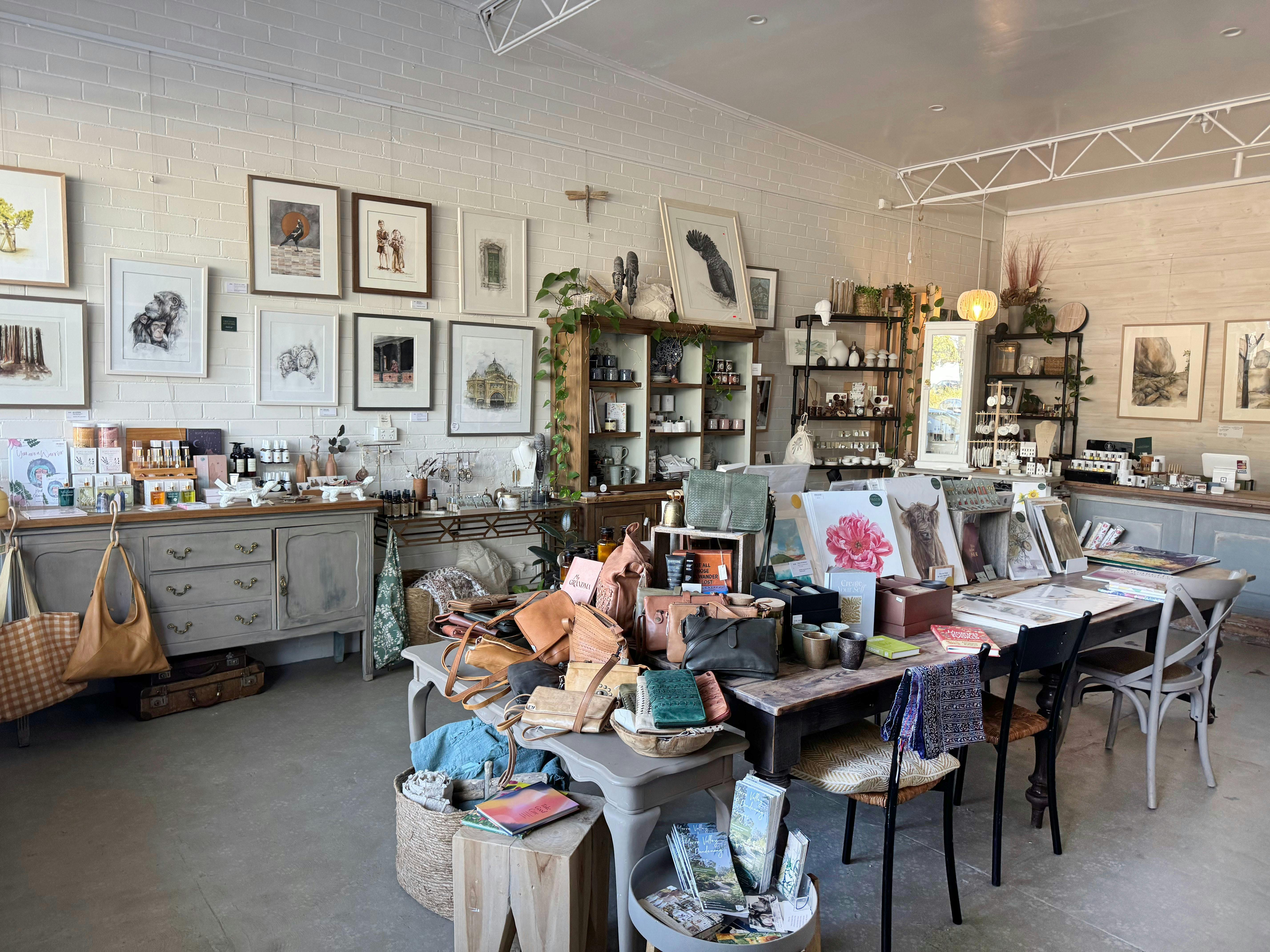 inside of shop showing big table woth card print art on wall