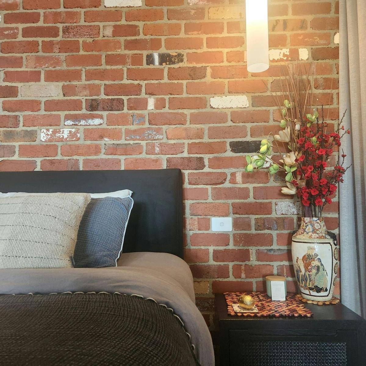 Bed postioned in front of recycled brick wall