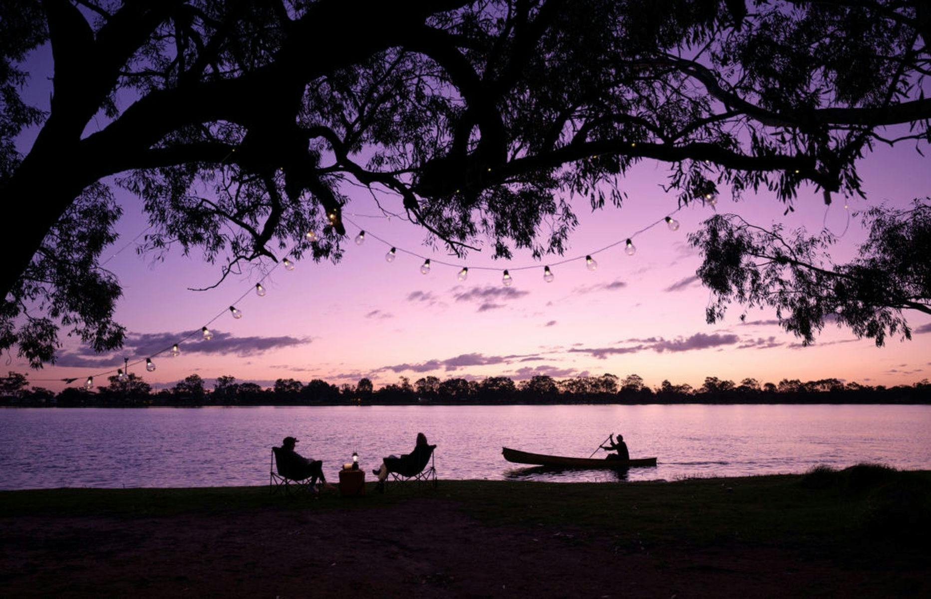Twilight photo of people sitting on the bank of the lake