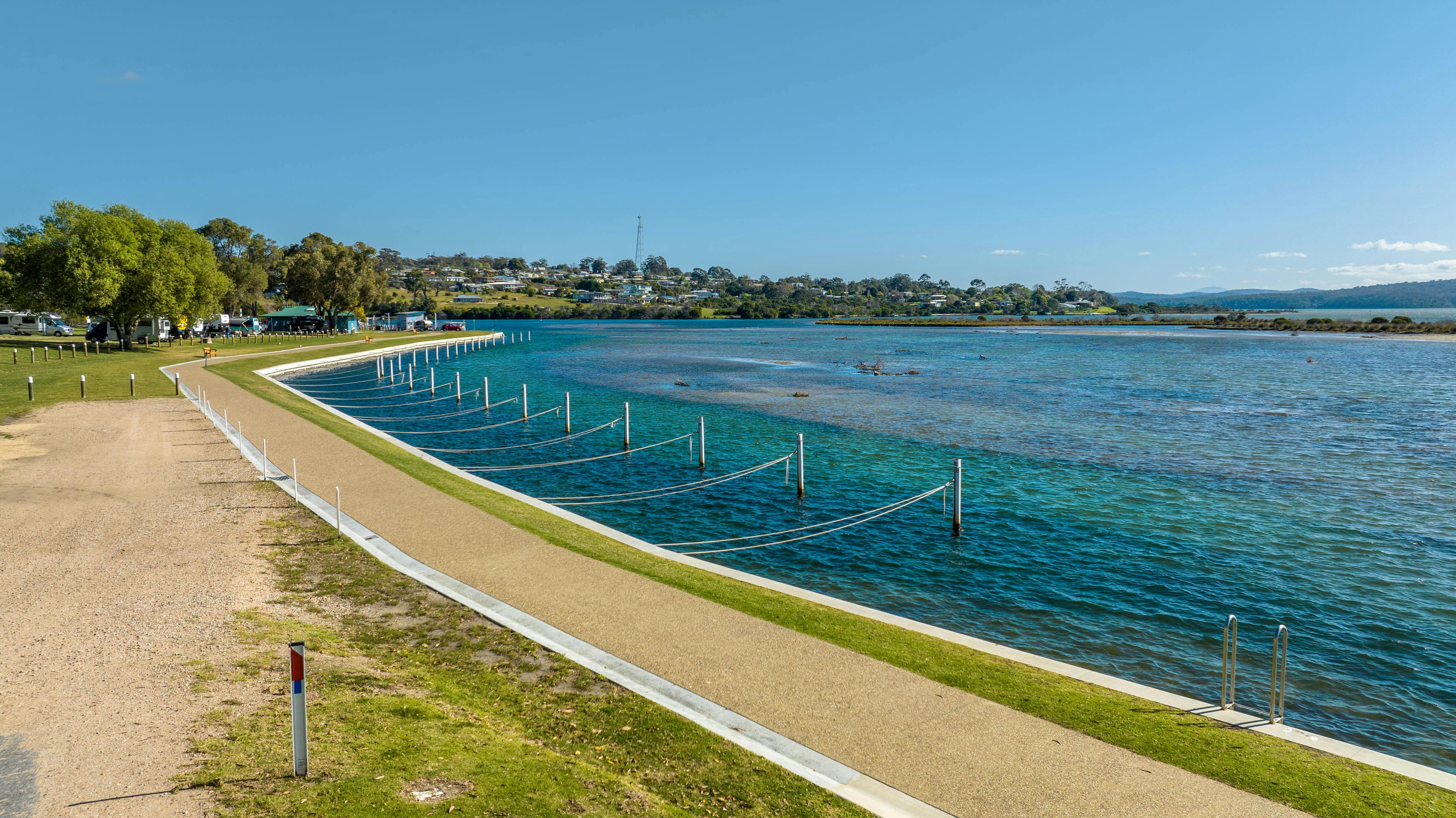 Walking path along the water beside boat moorings and blue water