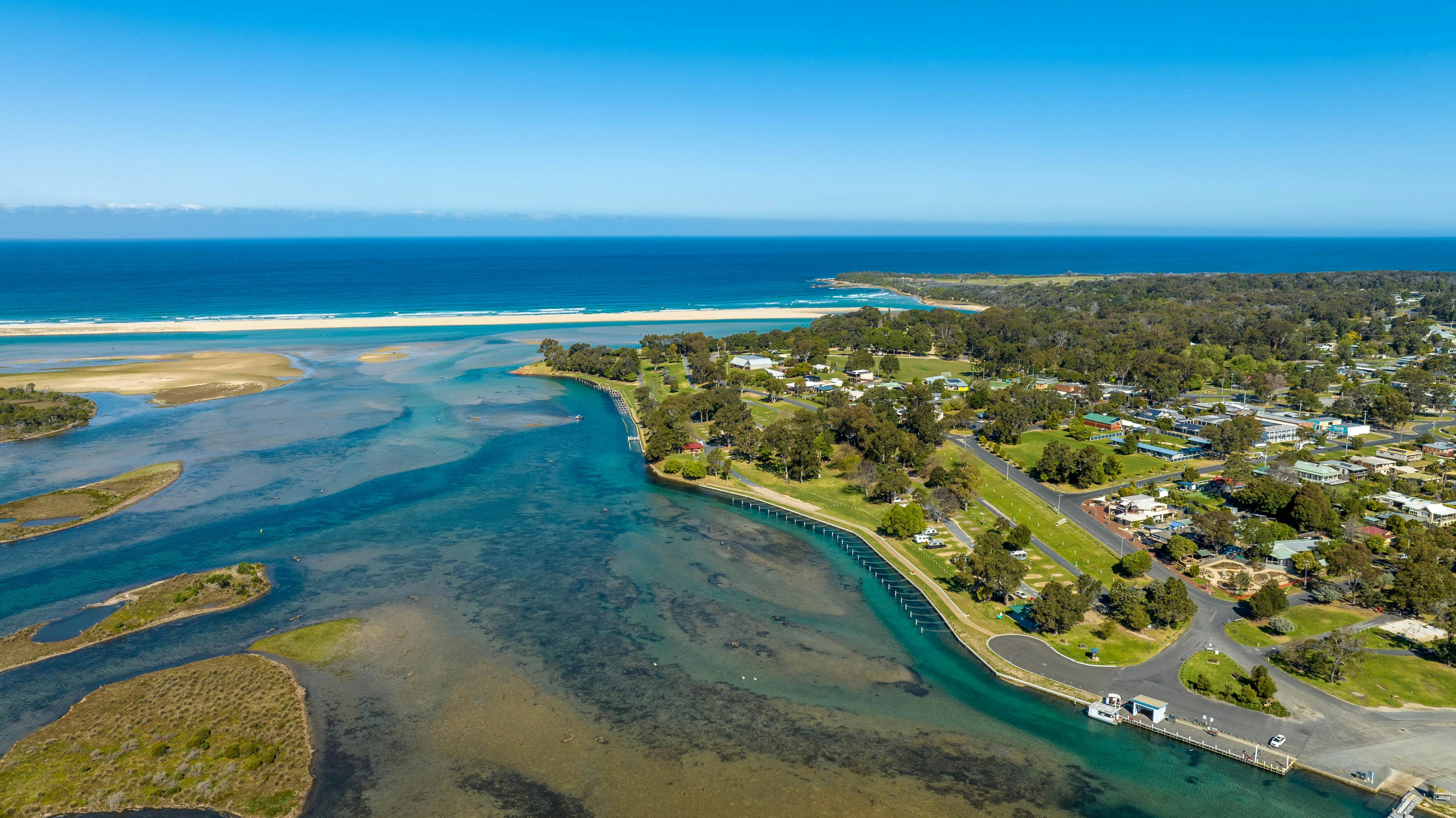 Aerial view of a Mallacoota Holiday Park, surrounded by lush greenery and water views