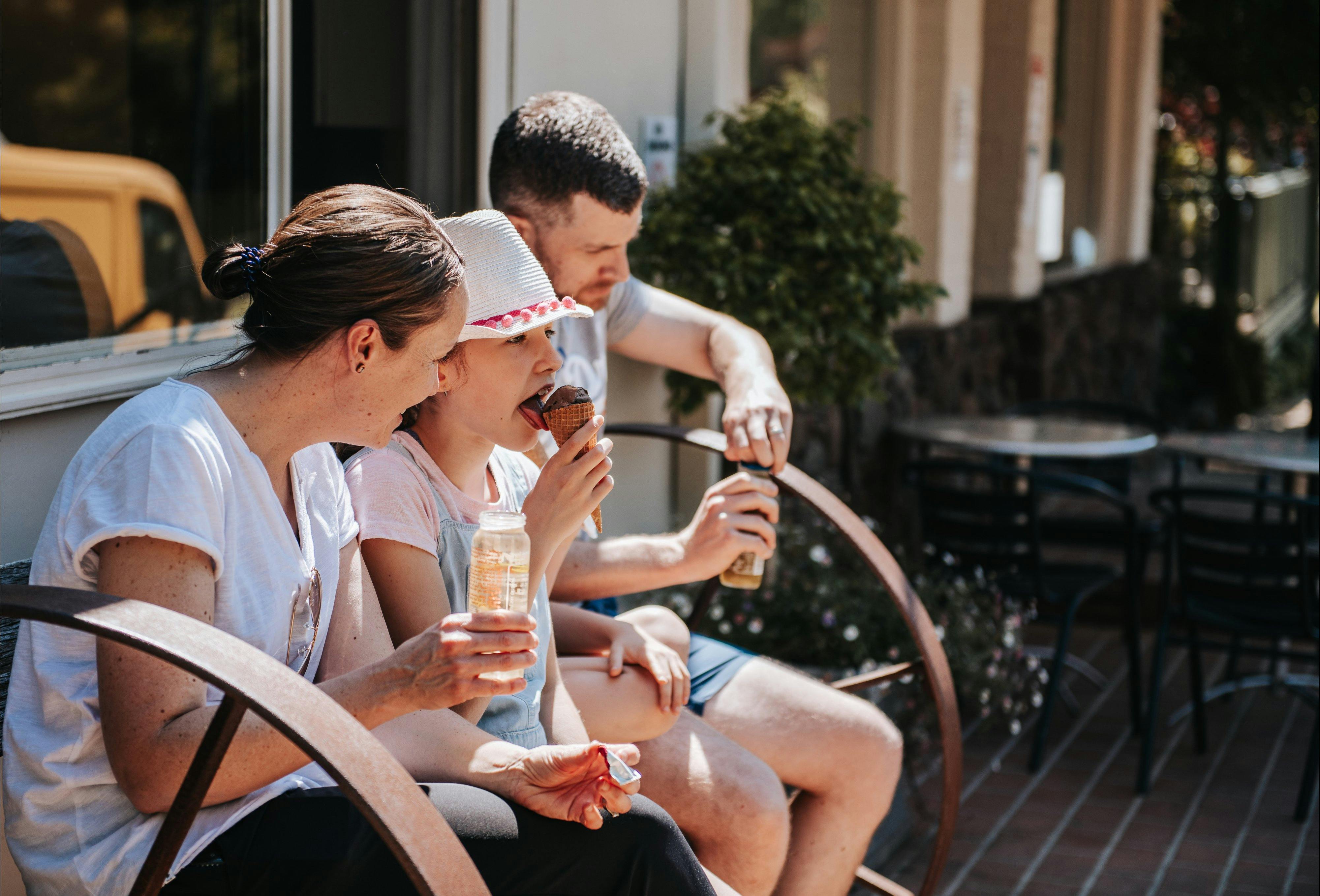 People eating and drinking on a bench