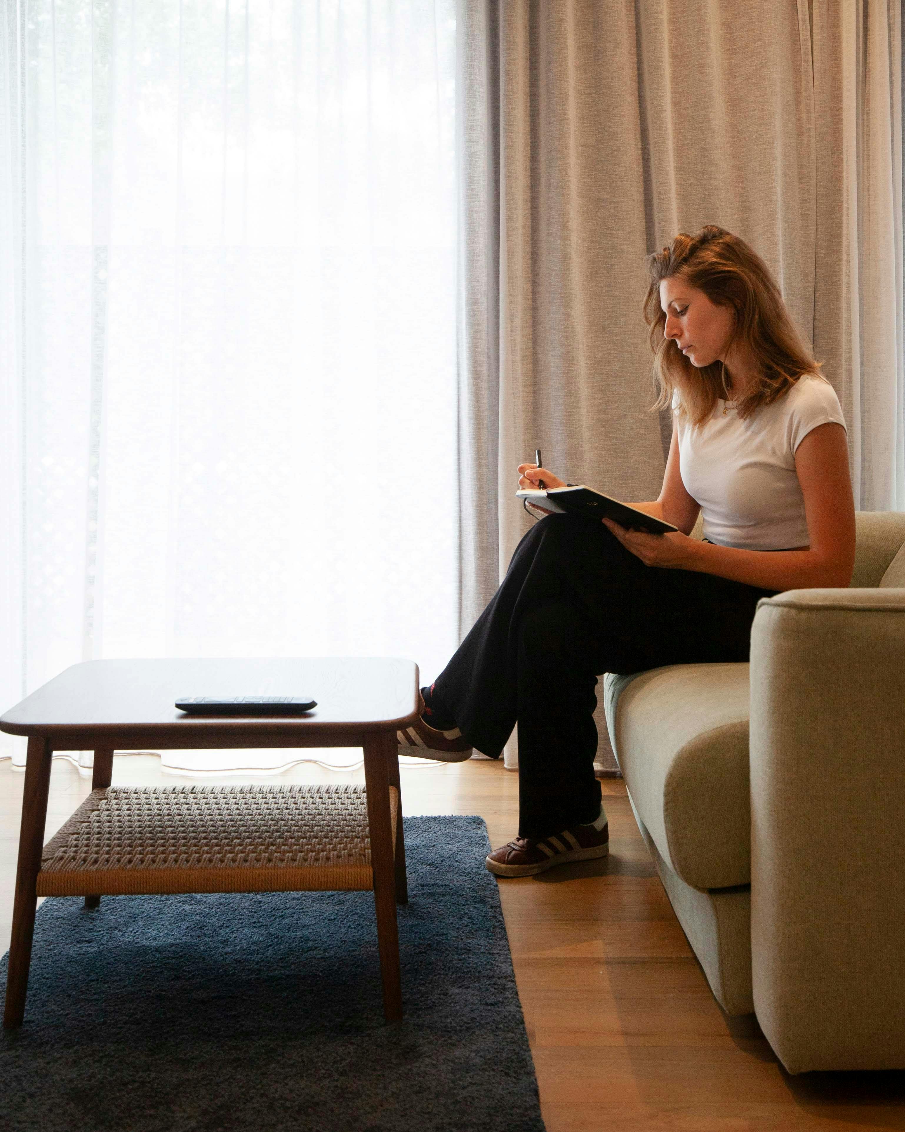 a woman sitting on a chair and writing in a diary