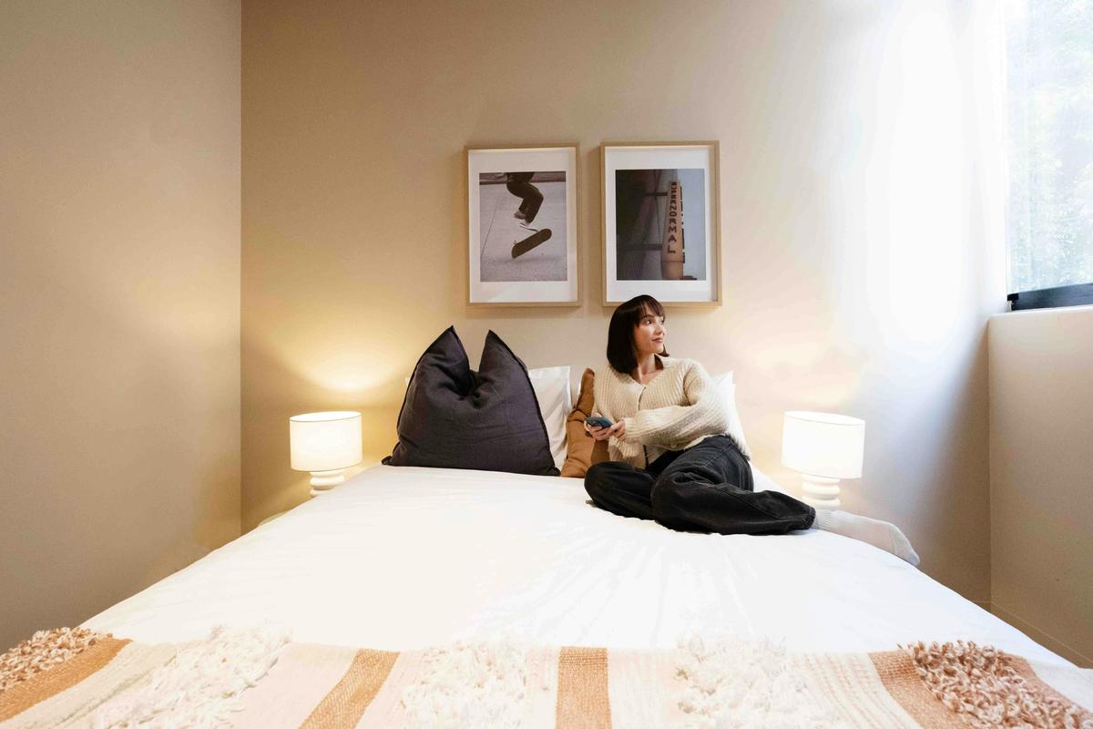 A guest lying on a bed in a hostel room