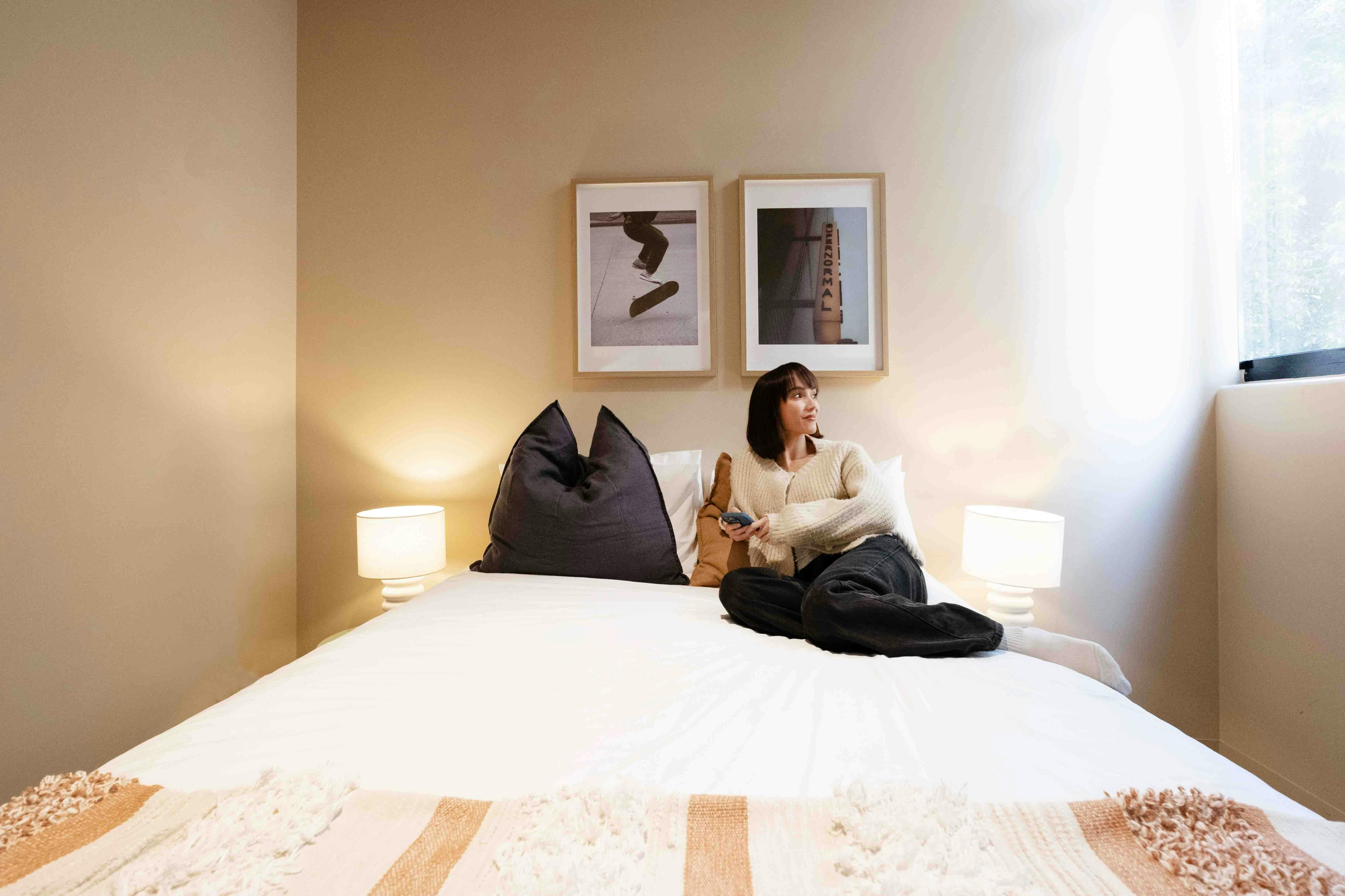 A guest lying on a bed in a hostel room