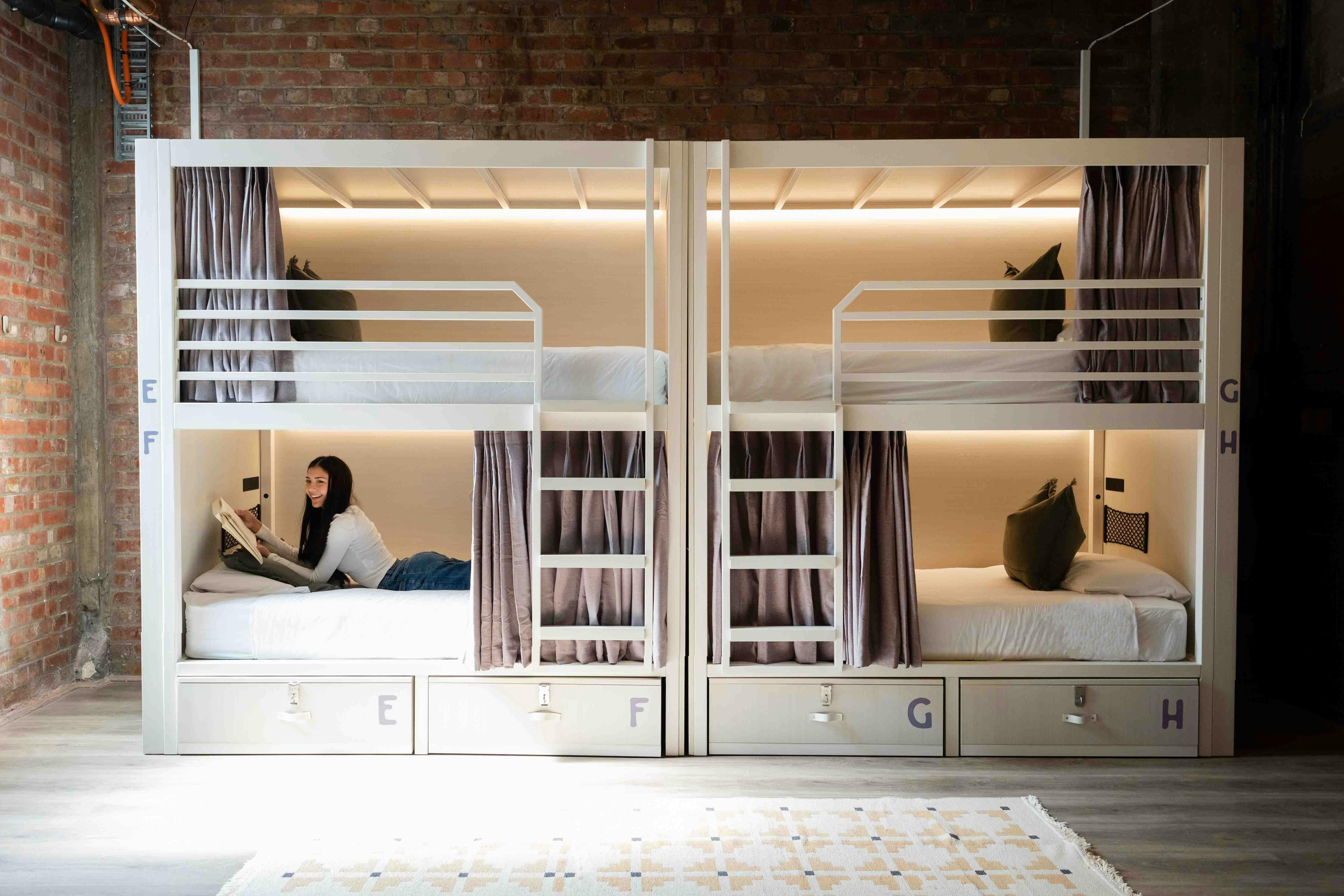 A guest reading within a hostel dorm bunk bed