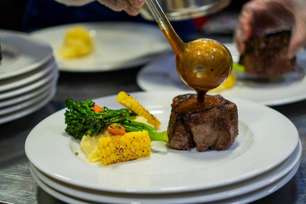 chef pouring sauce on another meal option for cruise