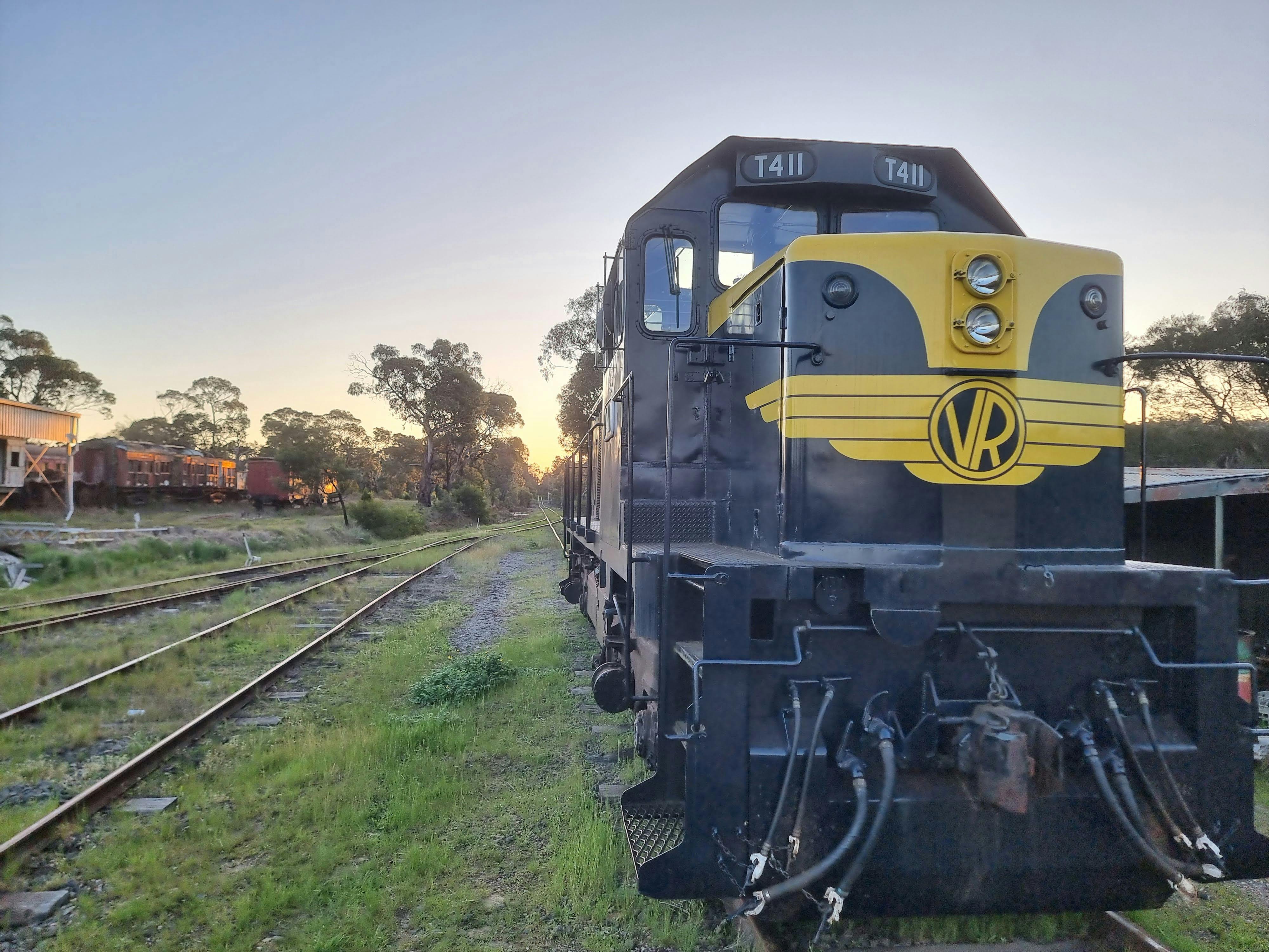 Yellow and black steam train with a sunset setting behind