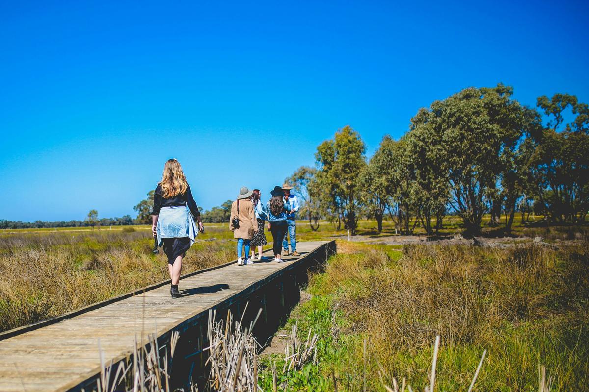 three people walking across a bridge