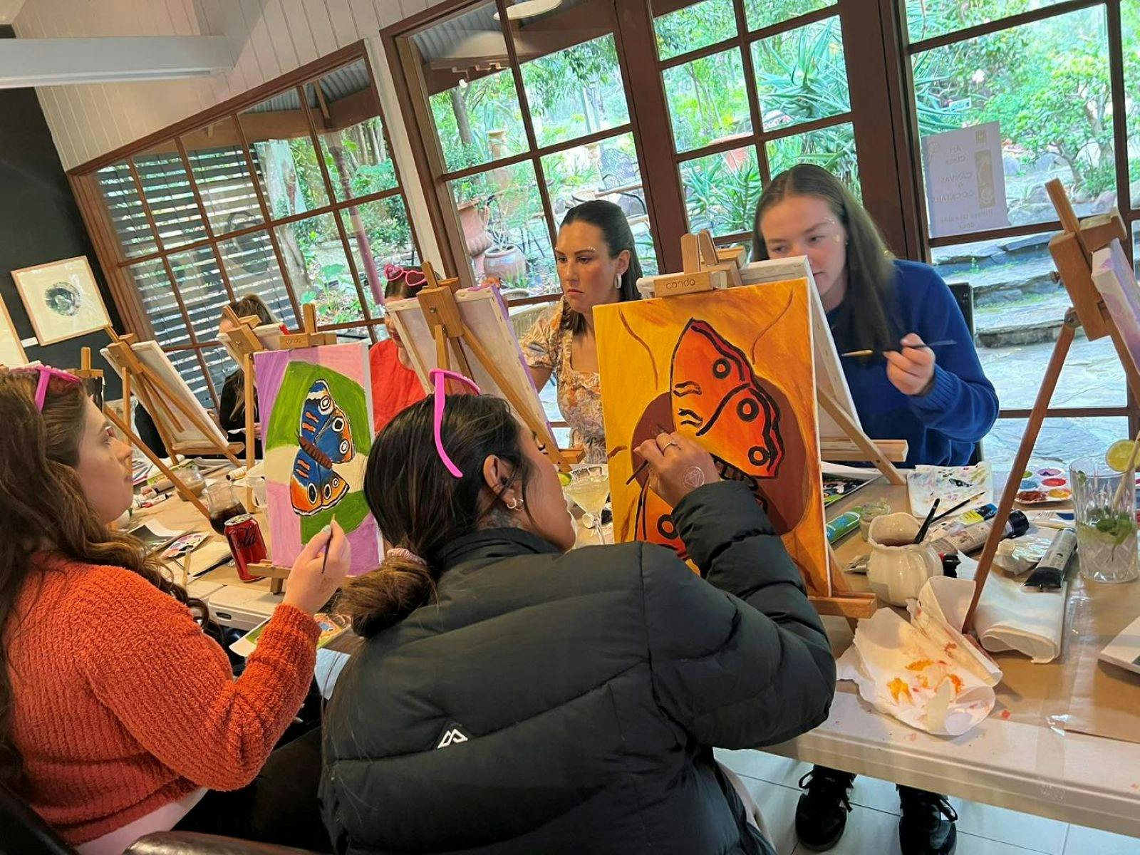 Group of young people sitting at easels and painting