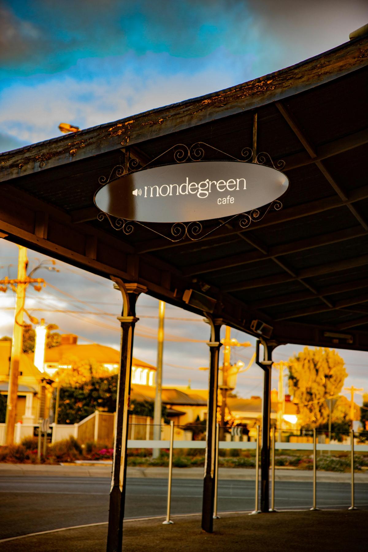 Oval sign of Mondegreen Cafe's logo under the front veranda.