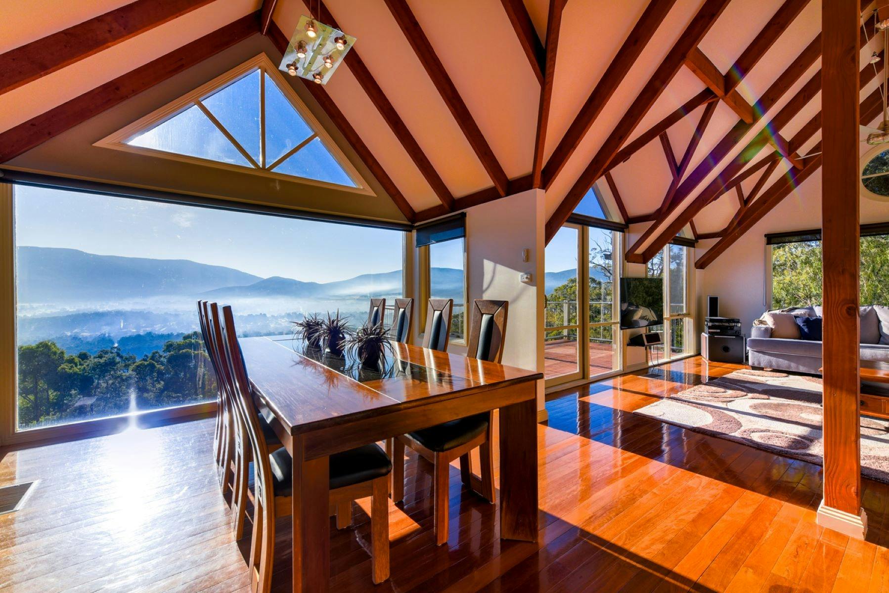 Living space filtered with light and views and exposed timber beam architectural ceiling