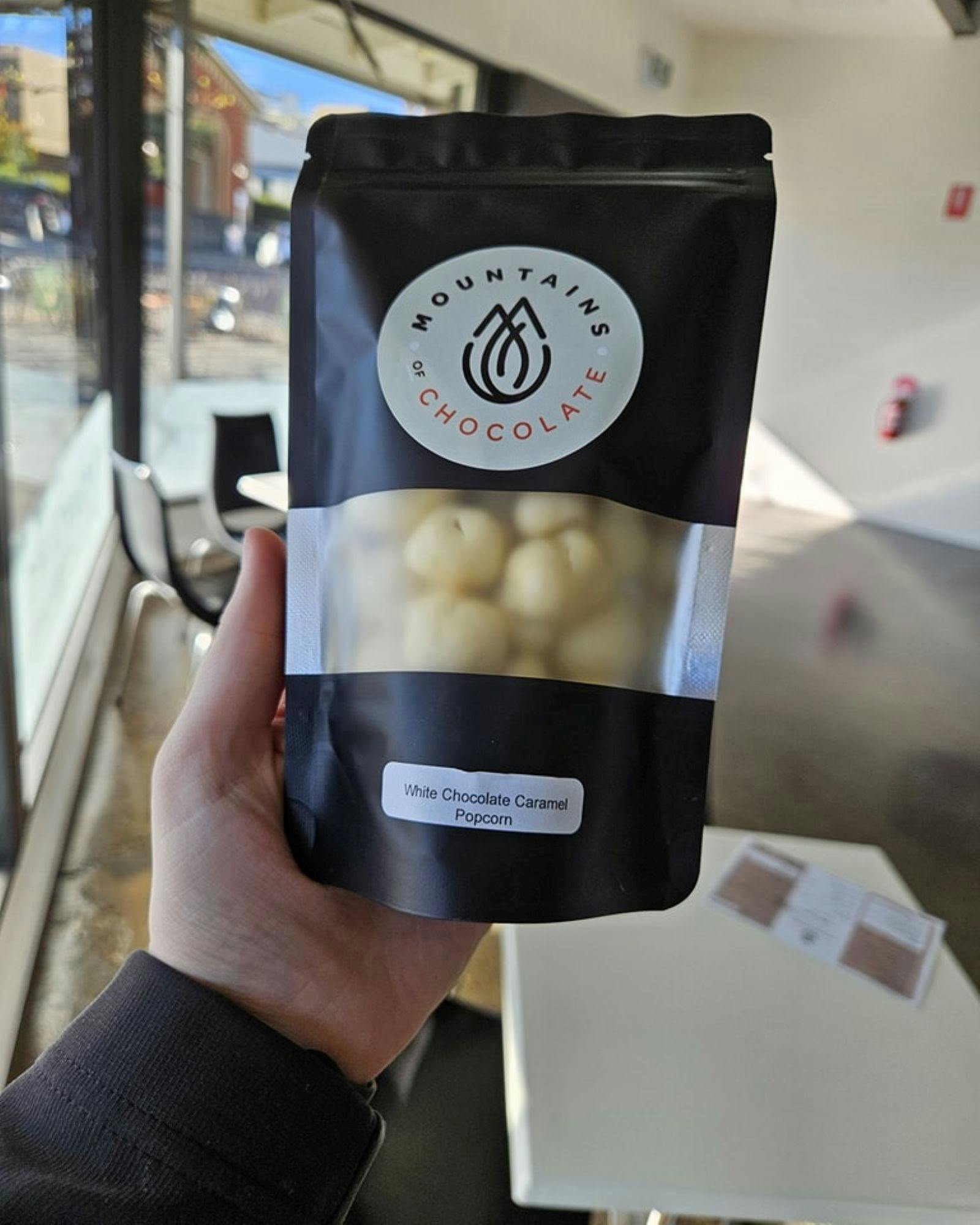 Hand holding a bag of white chocolate covered popcorn