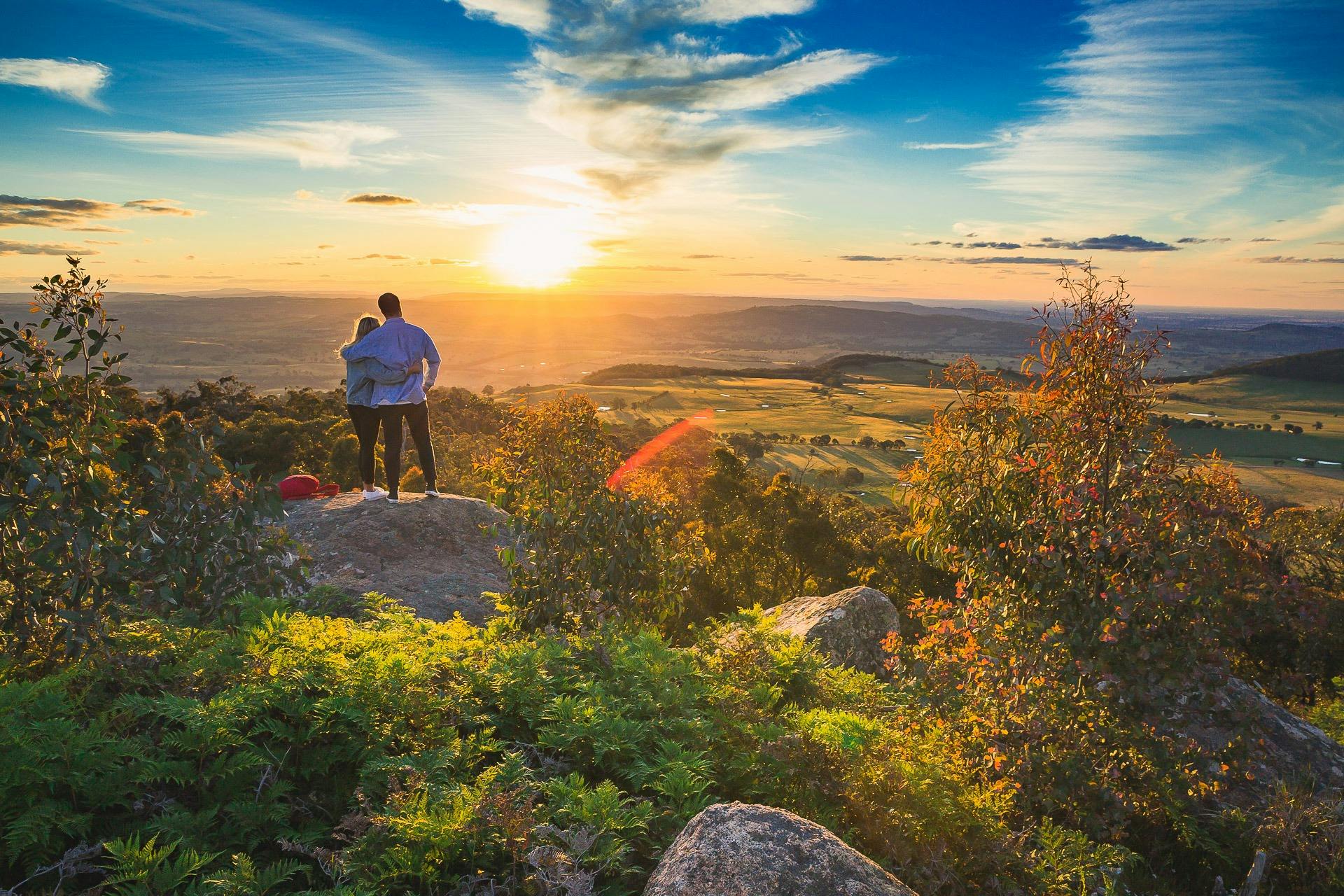 Lookout at sunrise - Couple standing on a rock