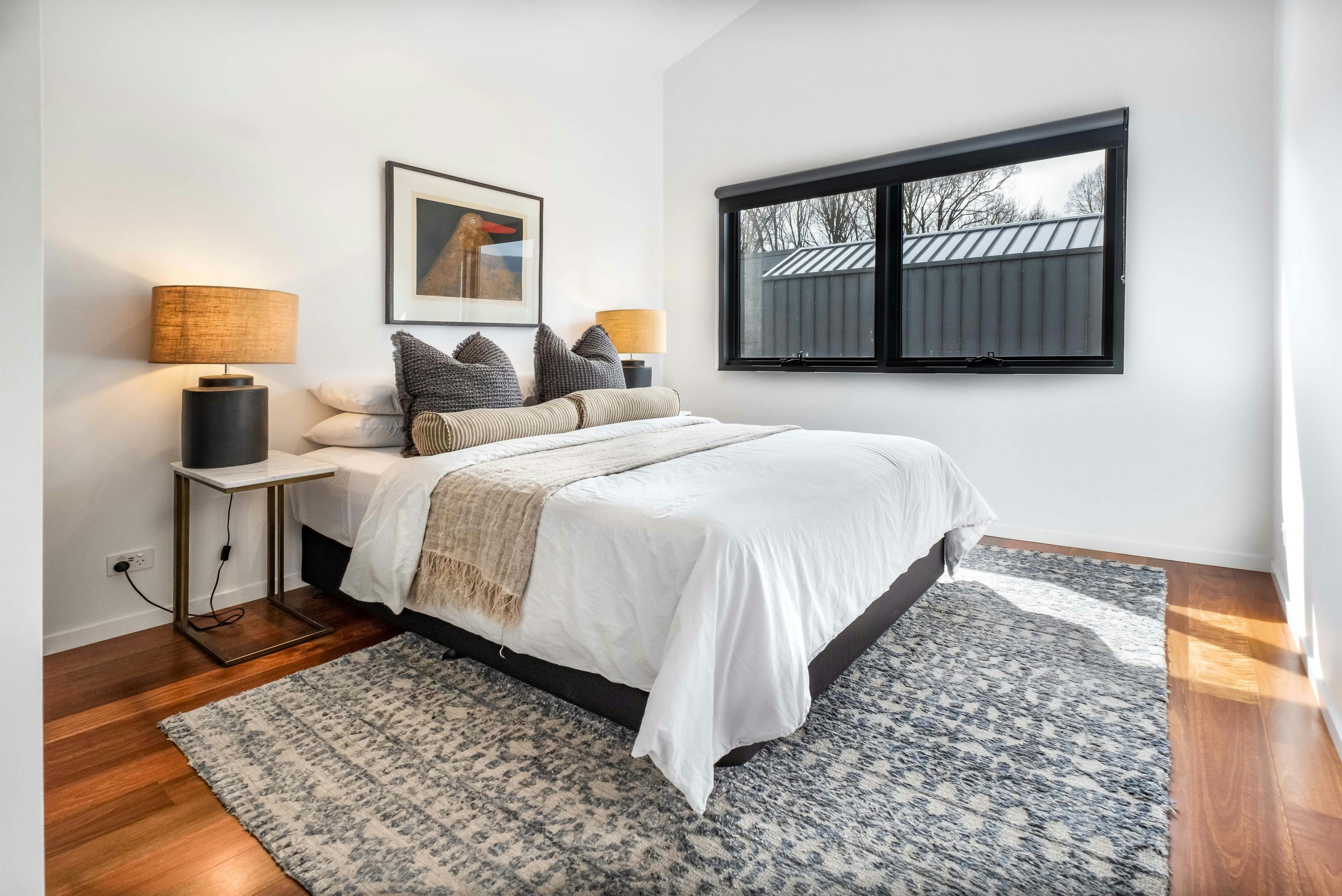 Olsen Penthouse bedroom with bed, tableside lamps and window