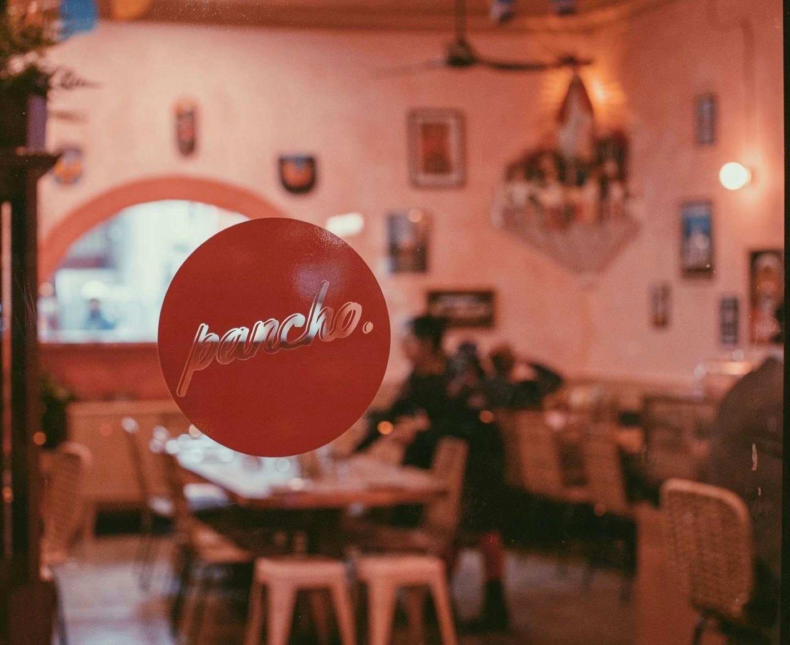 Window with round red pancho decal with restaurant tables behind
