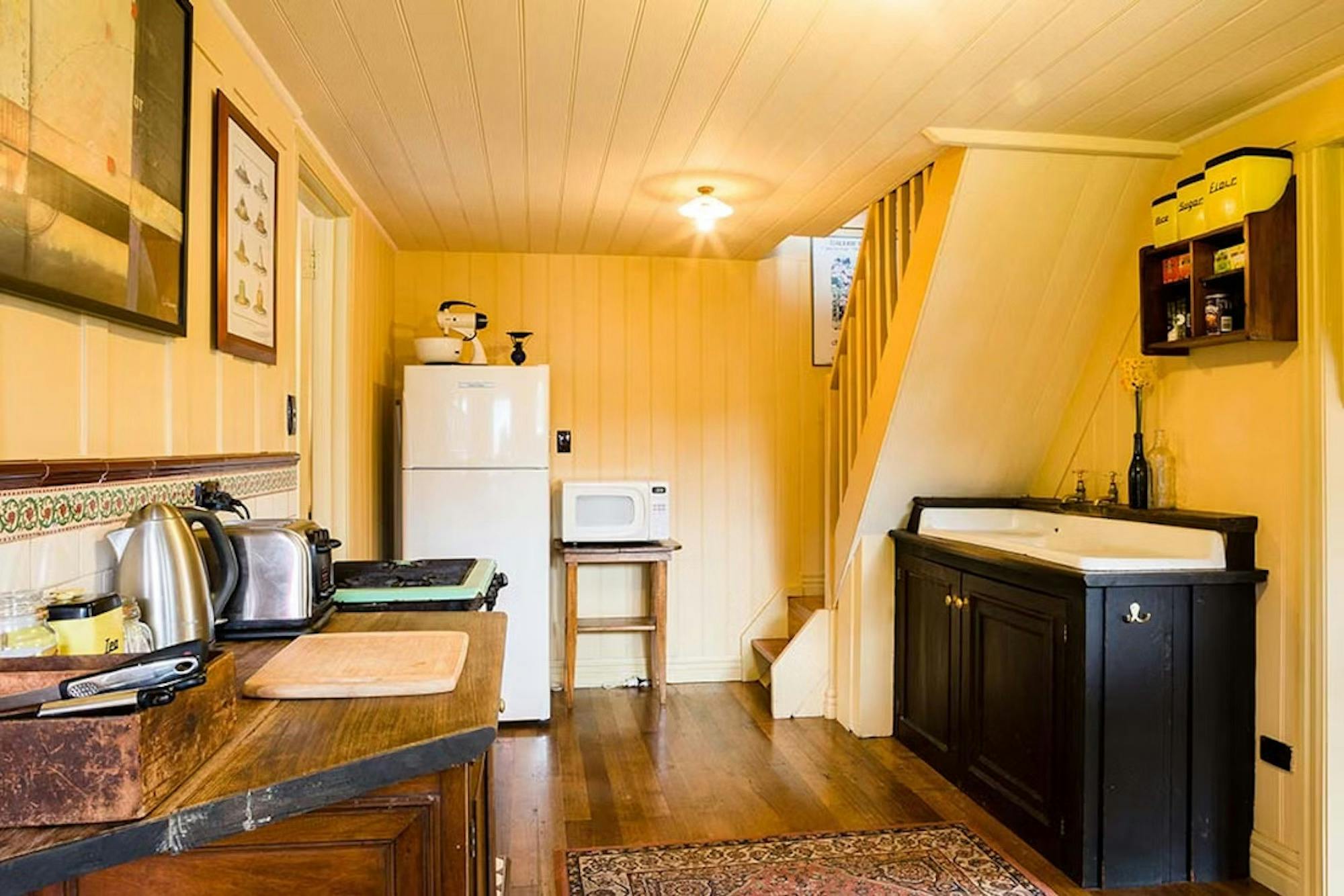 Lavender kitchen including fridge, microwave on a table and other kitchen amenities