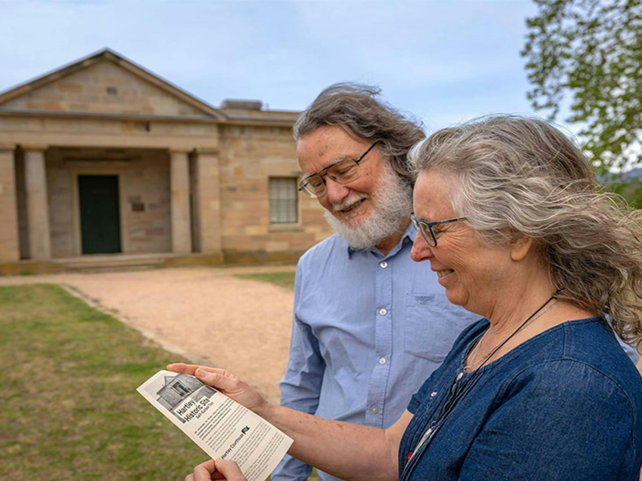 2 people reading a pamphlet in front of Hartley Courthouse at Hartley Historic Site. Credit: John