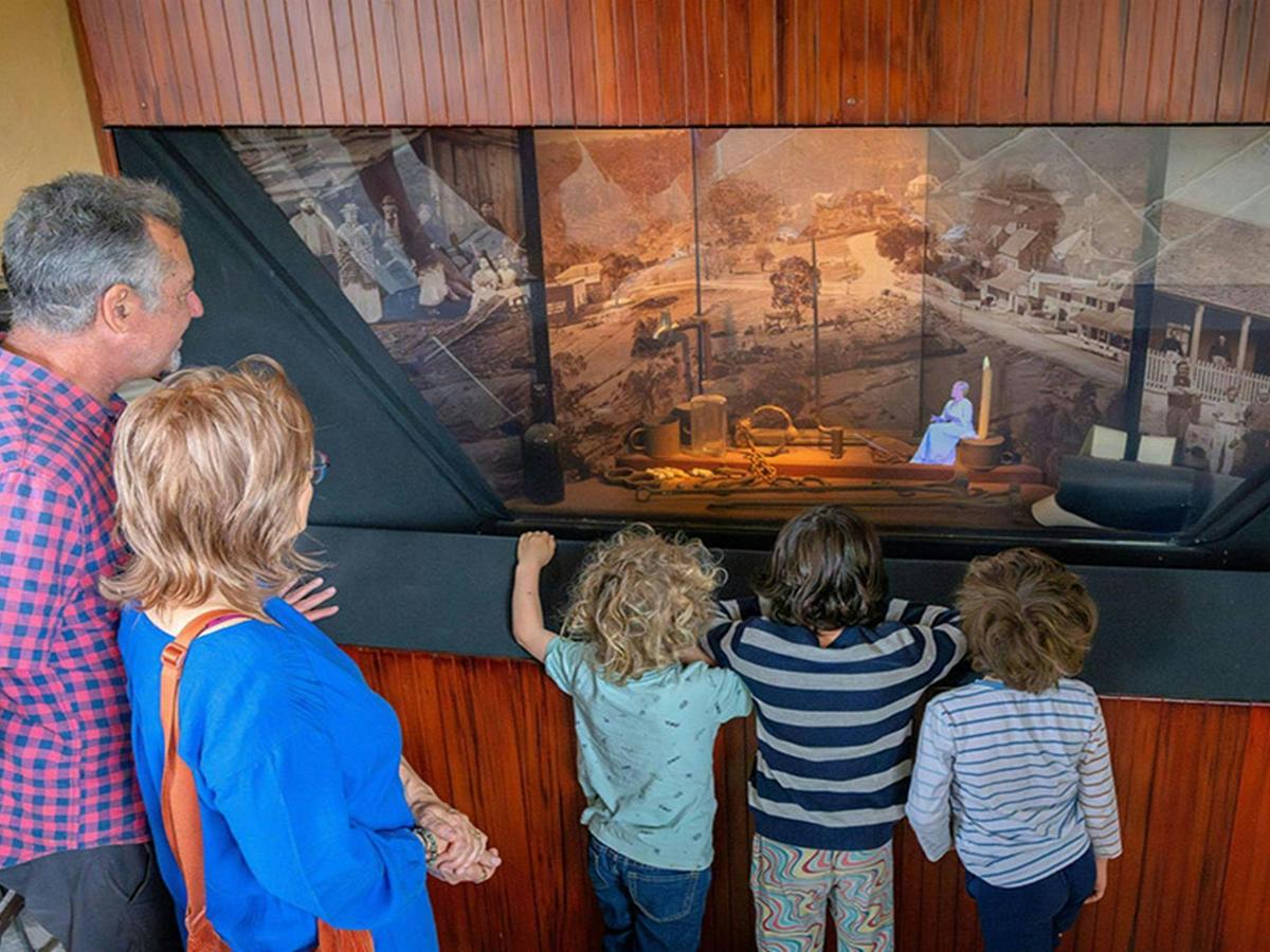 2 adults and 3 kids watching a hologram re-enactment of the historic court process inside Hartley
