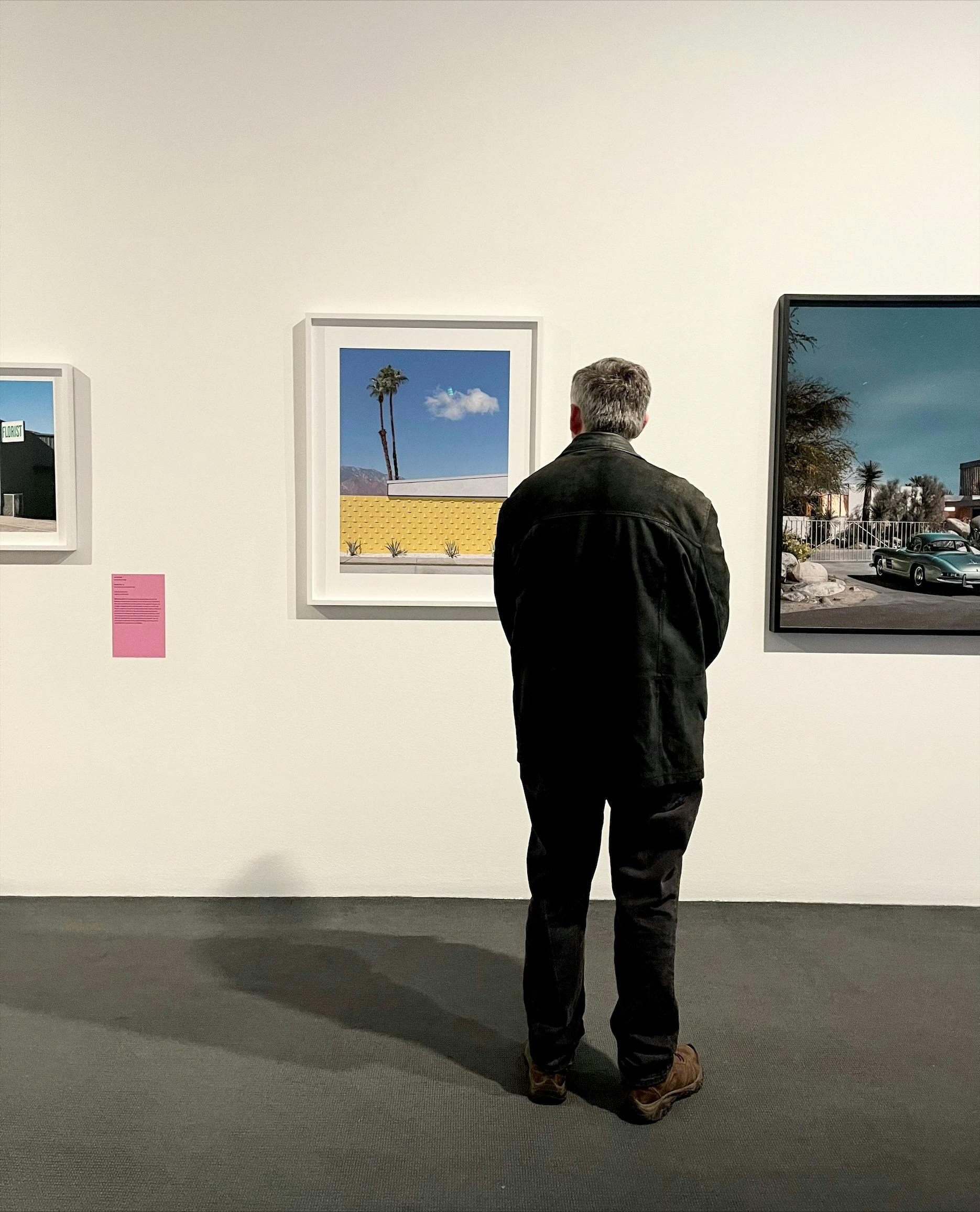A man views three framed photographs exhibiting in the Bowness Photography Prize 2023