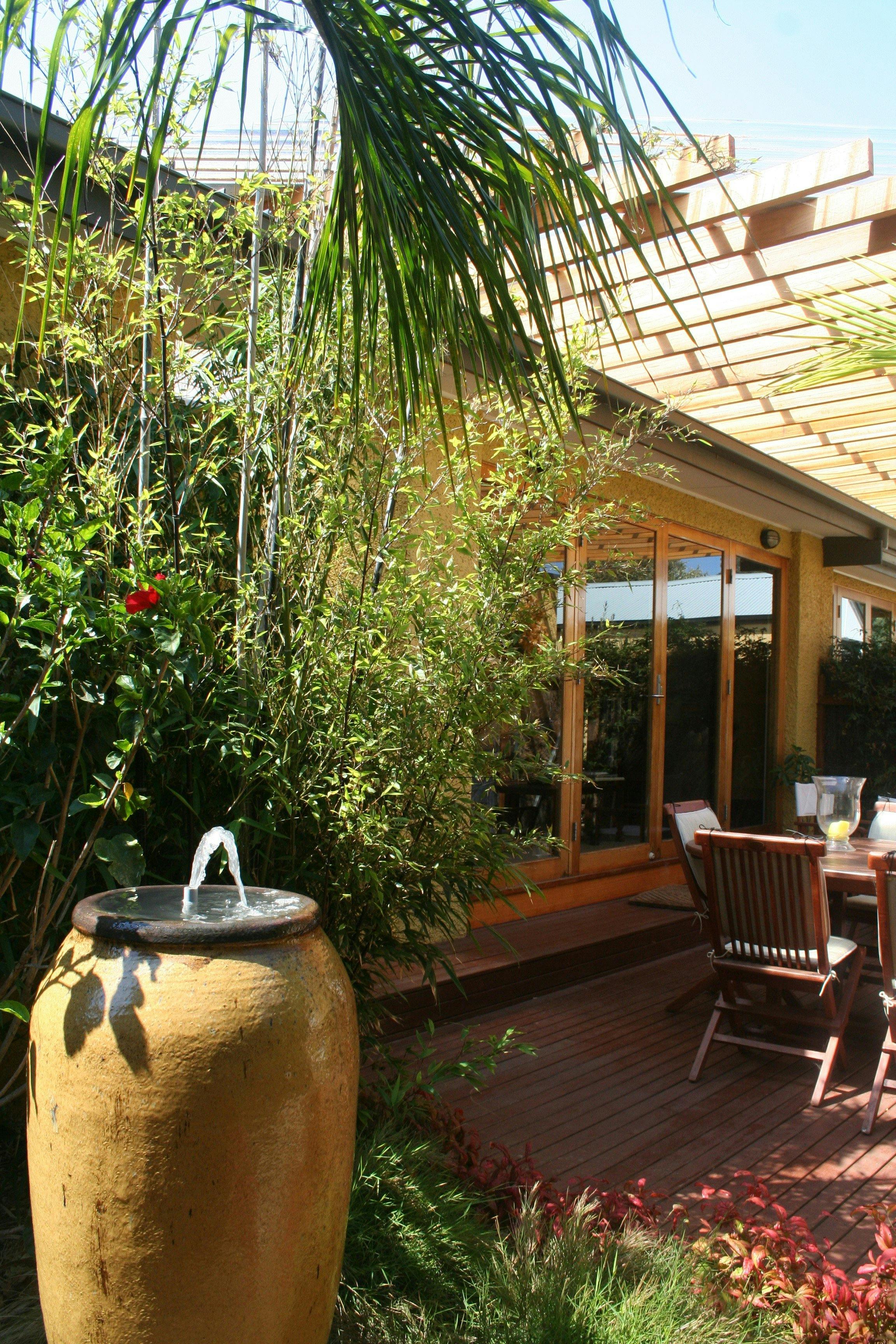 The rear Decking and an alfresco eating area. Set in a tropical garden there is an outdoor kitchen.