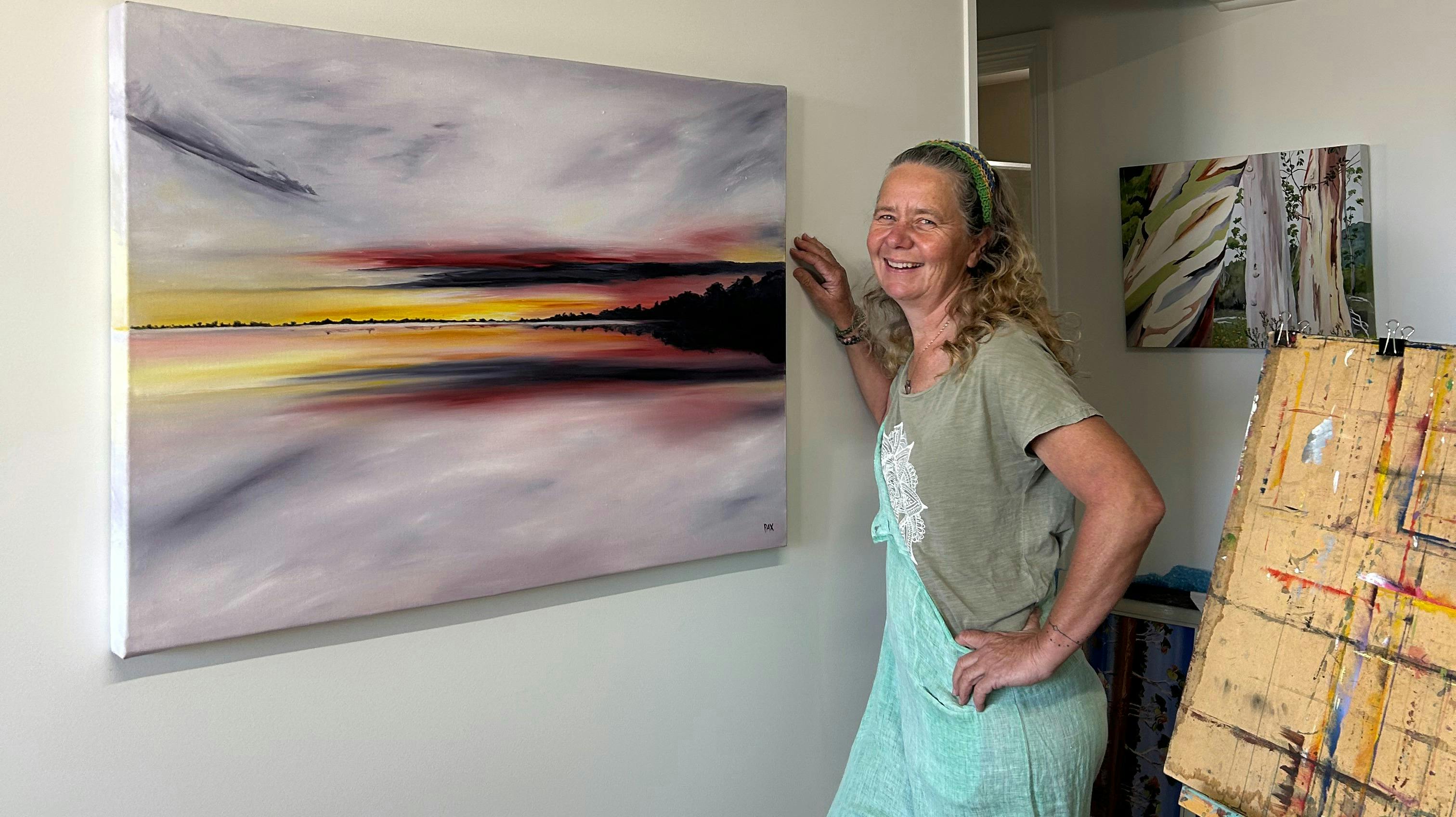 Artist Caroline Packer Pax with her painting Sunset Beach over Lake