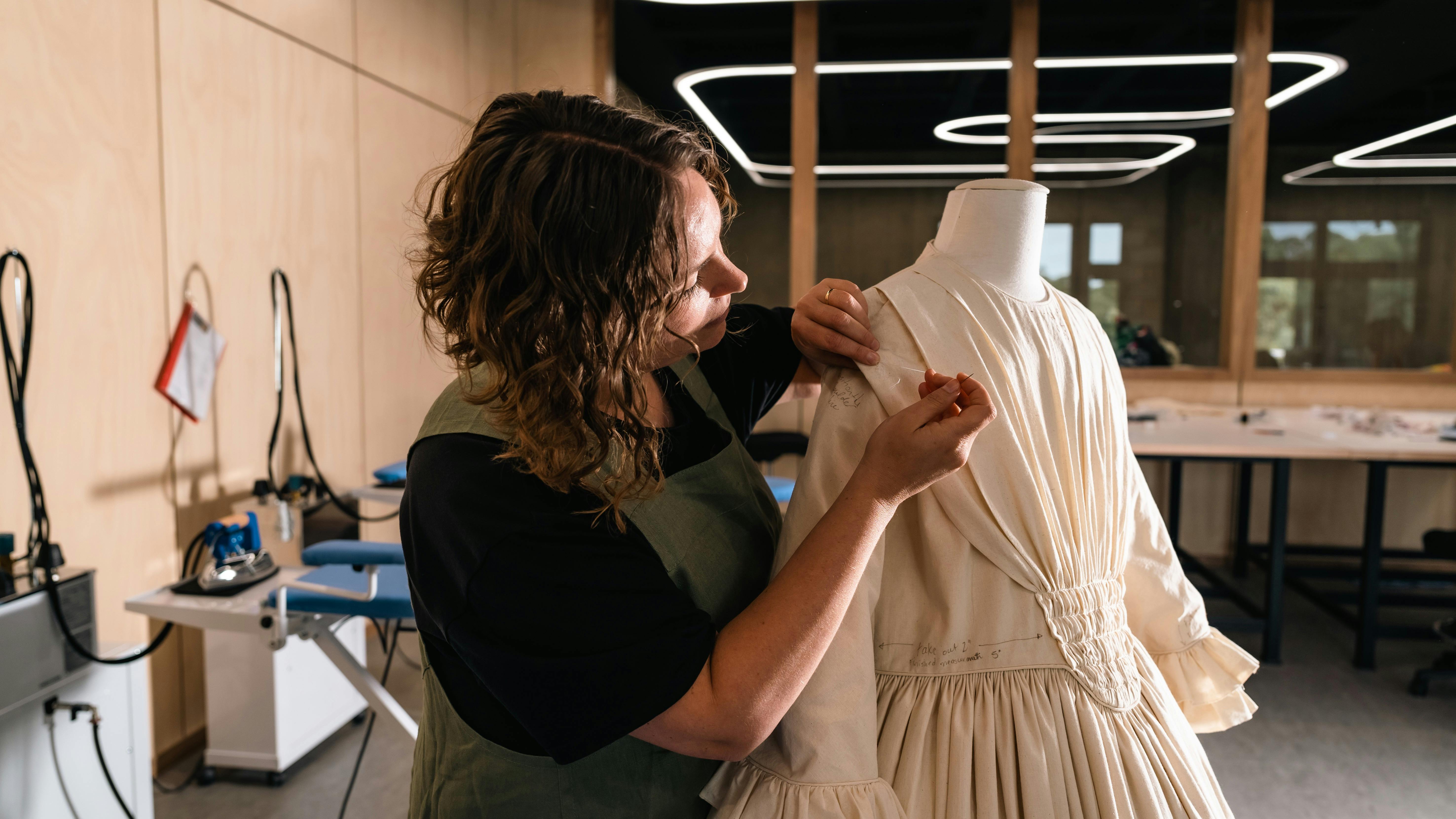 Costume maker pinning dress on mannequin