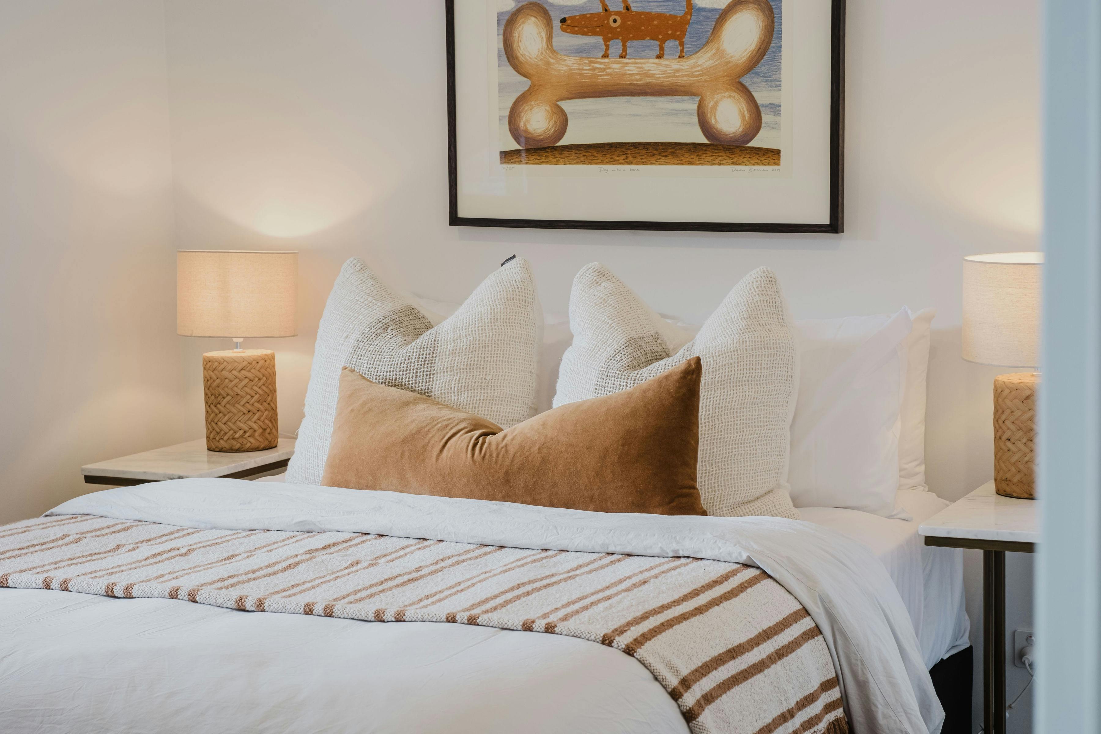 Reed arthouse townhouse bedroom with bed, table side lamps and painting on the wall