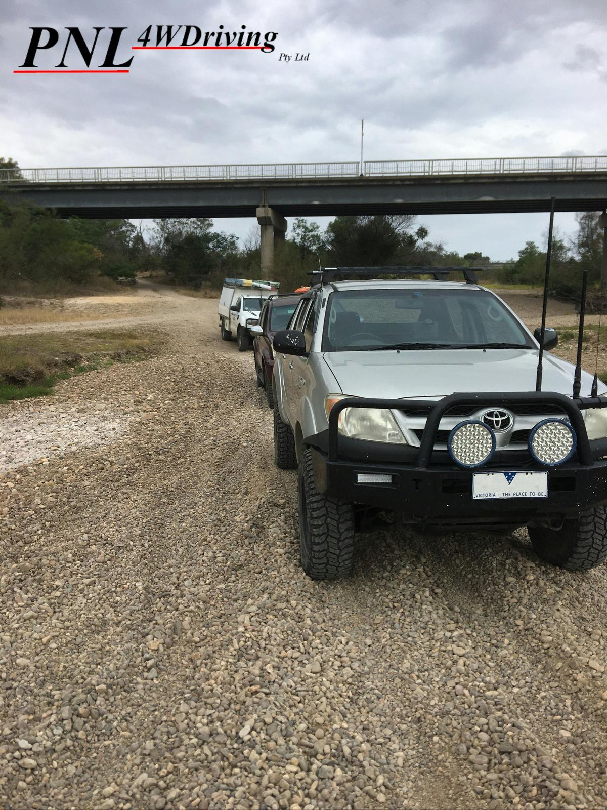 A convoy of 4WD's travel down a gravel track.