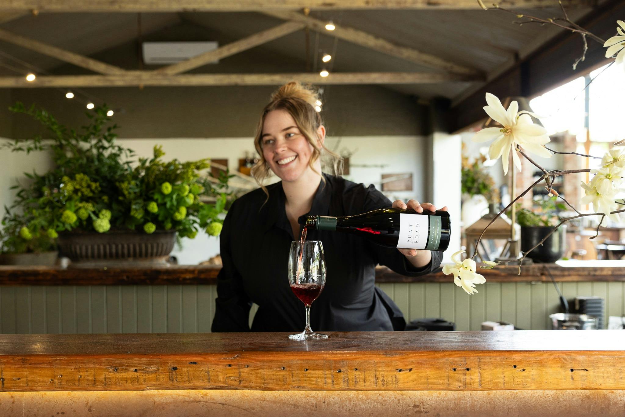 Staff member smiles as she pours wine
