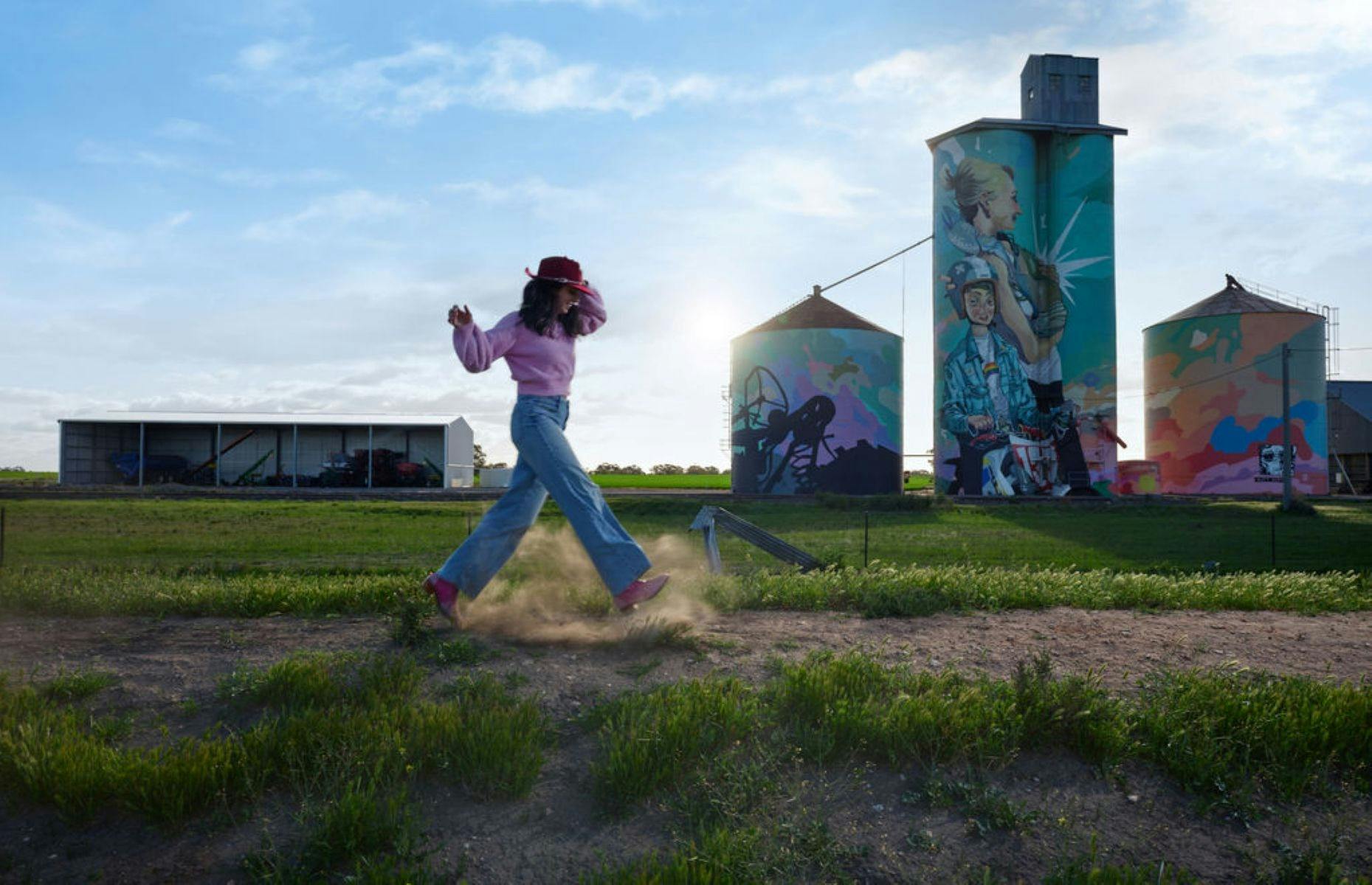 Person walking in front of painted silos in Rainbow
