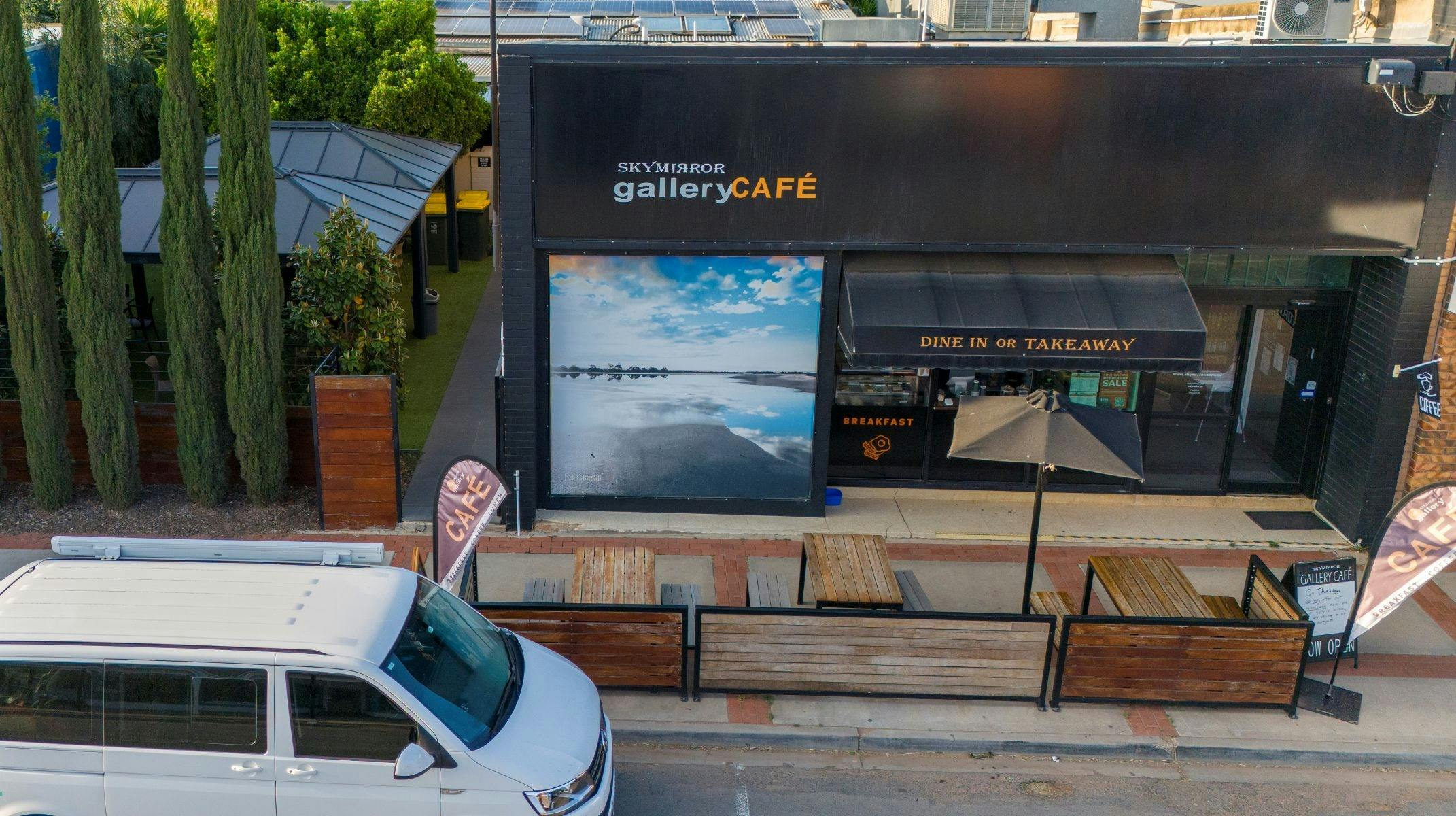 Aerial picture of the front of a cafe with a vehicle parked at the front of the shop