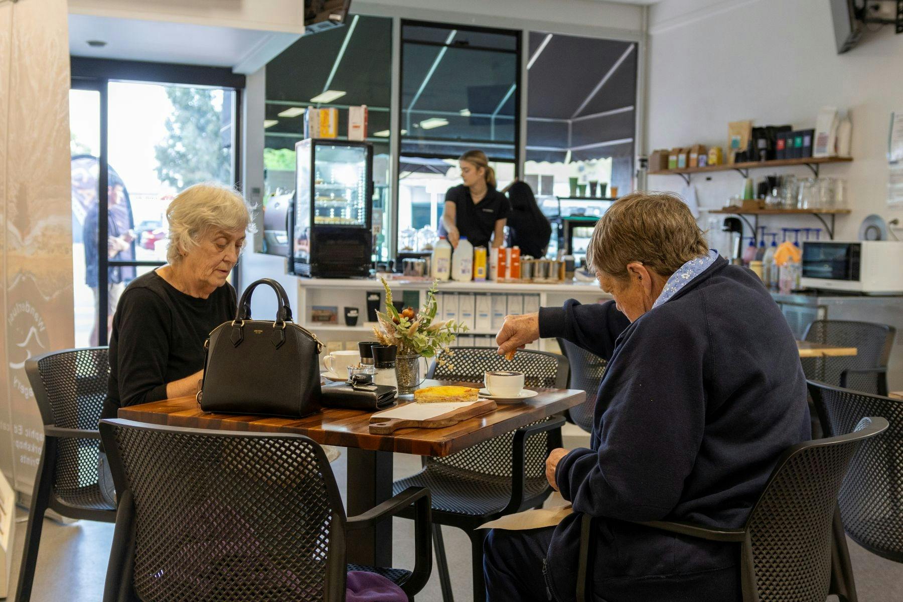 Two people sitting at a table enjoying a coffee and a counter in the background