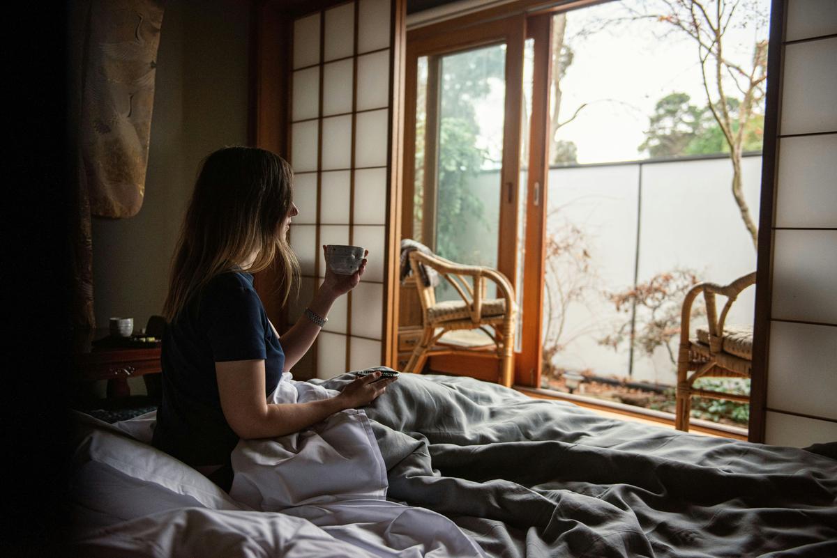 A woman waking up to the tranquility of Shizuka Ryokan with a cup of soothing green tea