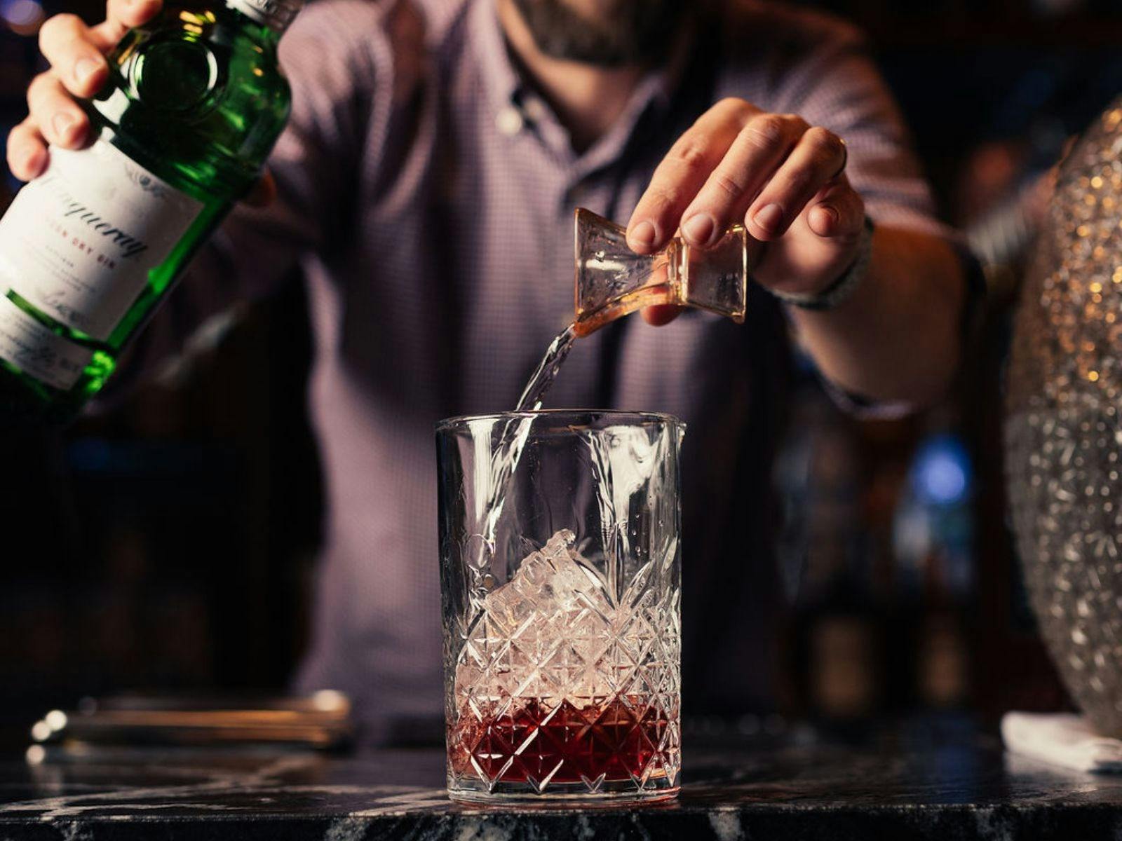 bartender pouring spirit in a glass