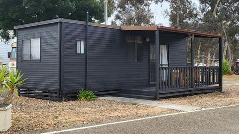 Black cabin 43 with a covered porch and outdoor seating at Stawell Grampians Gate Hotel Motel