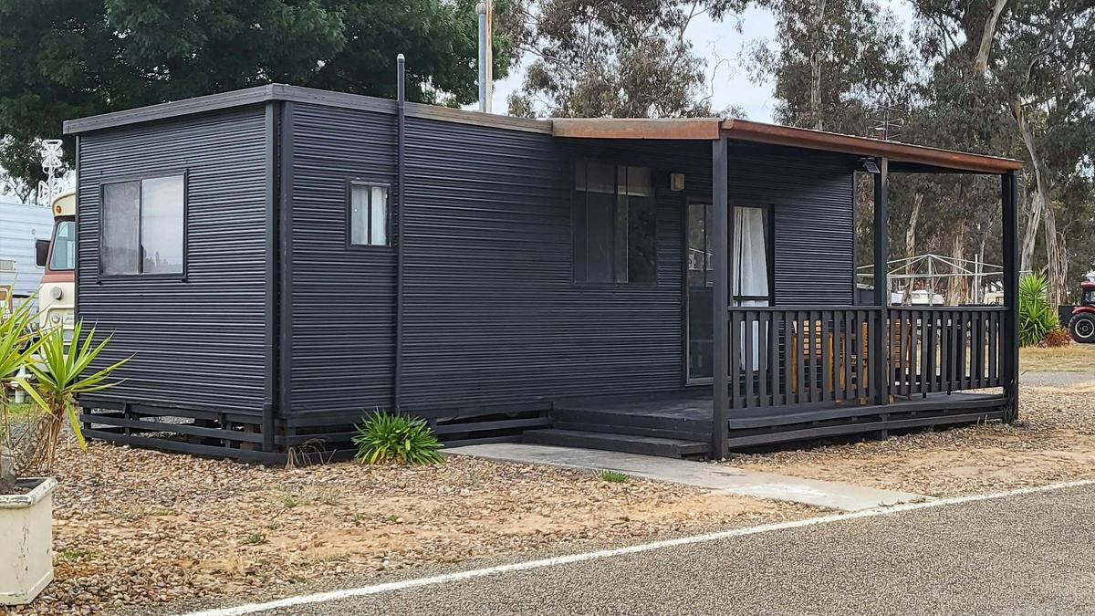Black cabin 43 with a covered porch and outdoor seating at Stawell Grampians Gate Hotel Motel