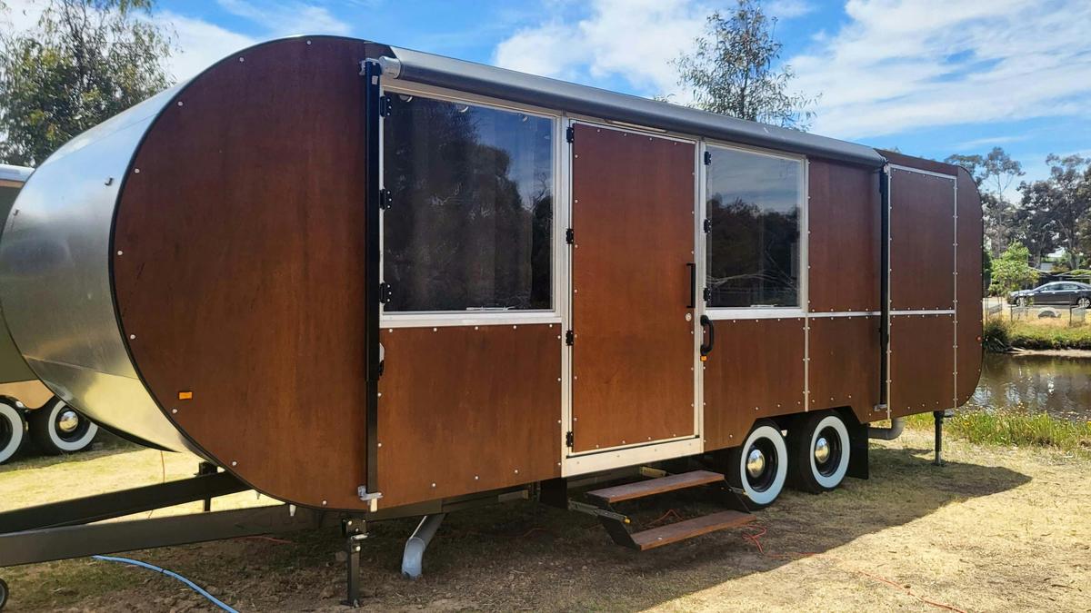 Brown caravan with large windows, parked by the riverside at Stawell Grampians Gate Hotel Motel