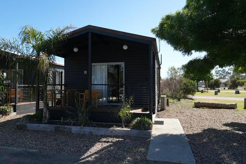 Black cabin with a front porch and outdoor seating at Stawell Grampians Gate Hotel Motel