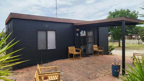 Black cabin 53 with a covered patio and wooden chairs at Stawell Grampians Gate Hotel