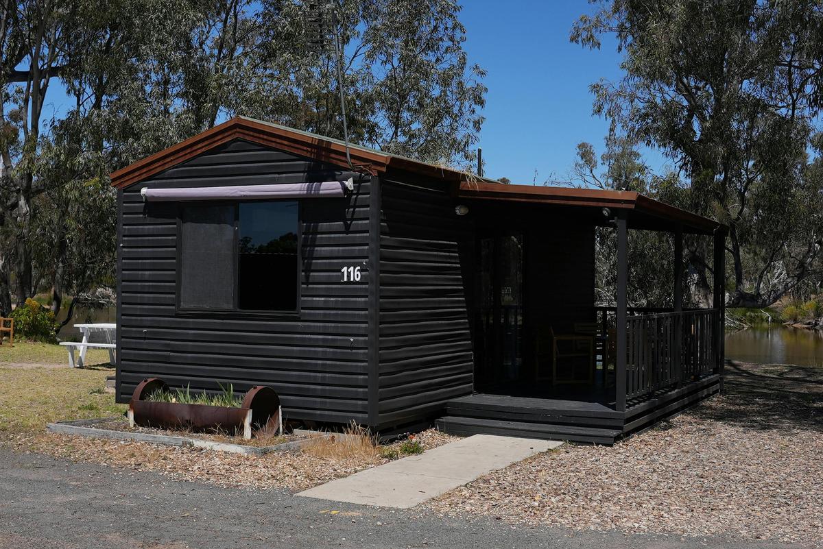 Black cabin 116 with a porch and outdoor seating location at Stawell Grampians Gate Hotel Motel